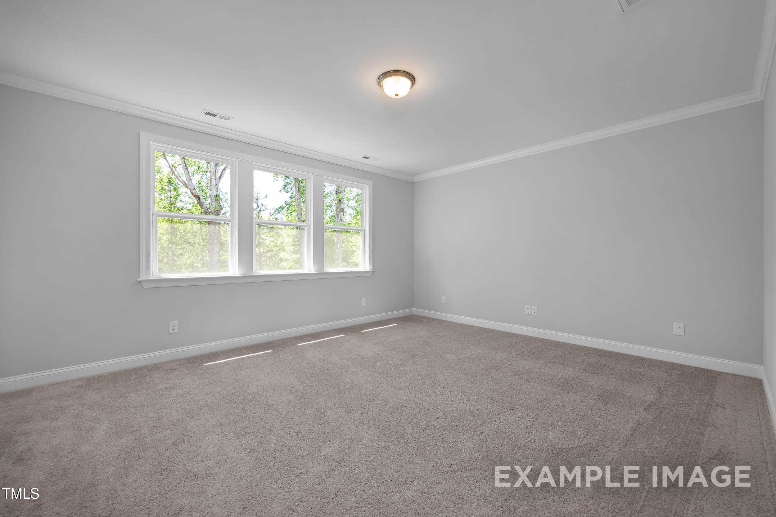 Bright empty bedroom with large triple windows, gray walls, and carpeted floor in Davidson Homes The Beech B, Raleigh, NC