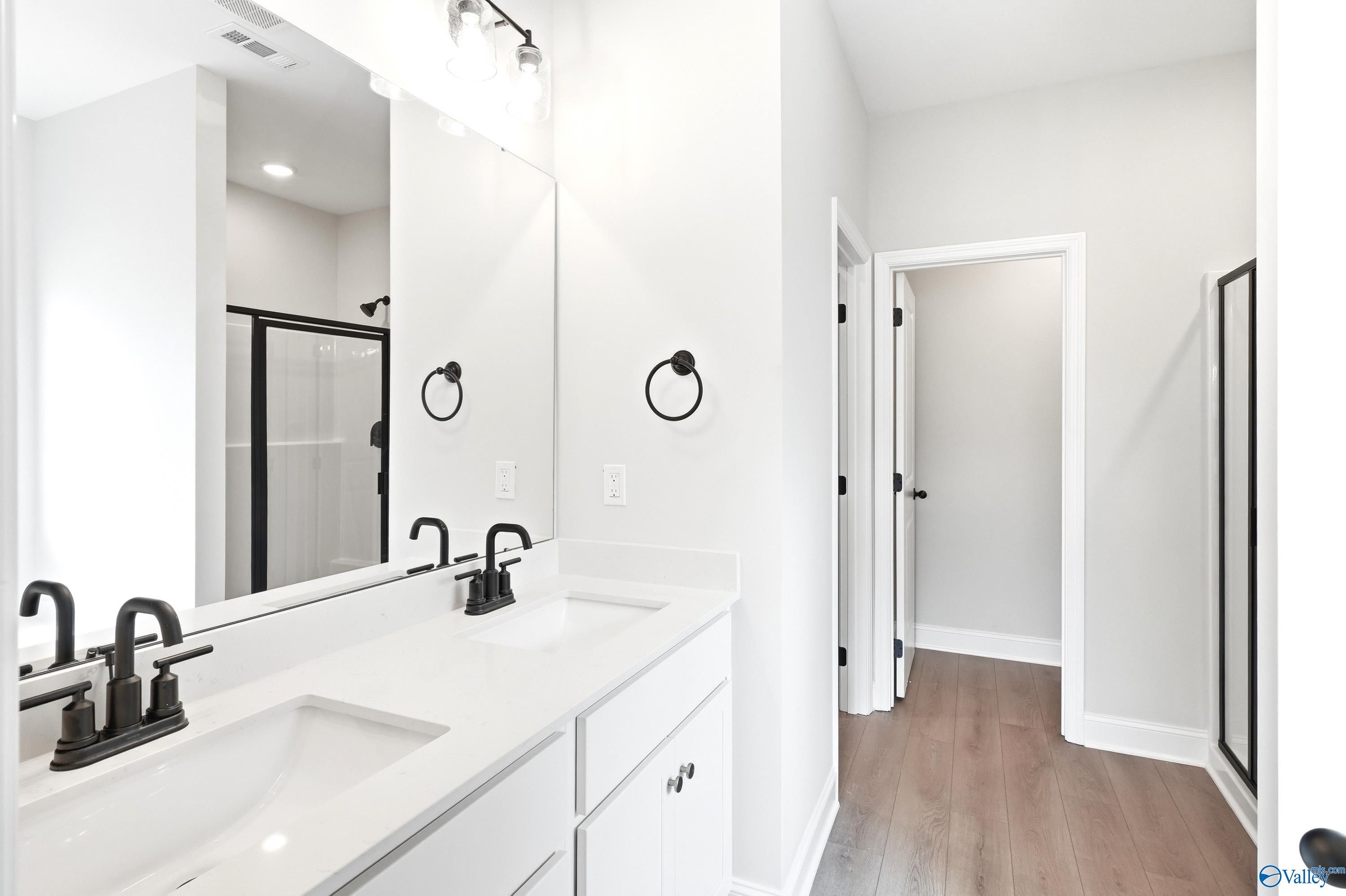 Modern double vanity bathroom with matte black fixtures in The Daphne floor plan at Lynn Meadows, Meridianville, Alabama.
