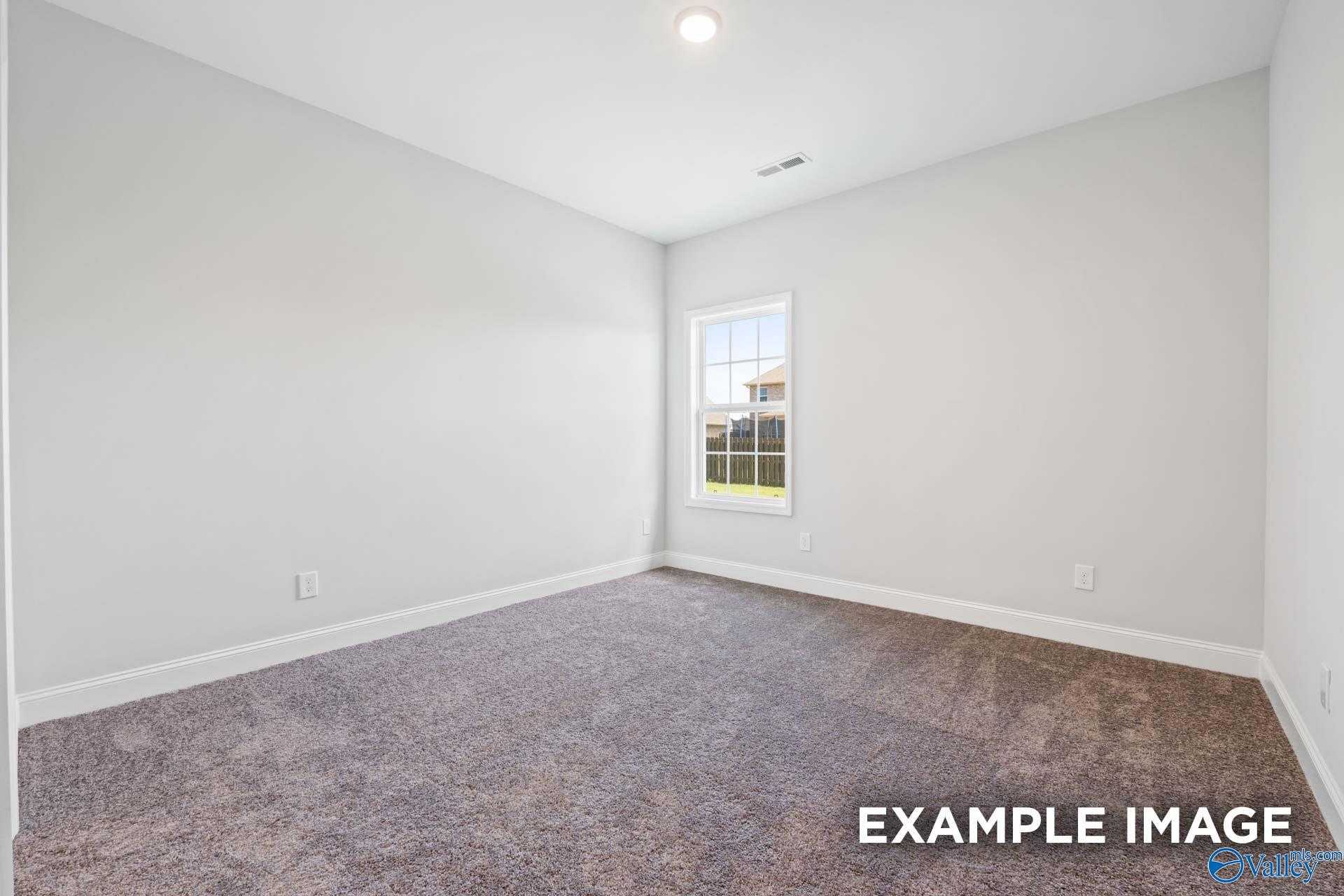 Bright secondary bedroom with light gray walls, beige carpet, and window view in 4-bedroom The Lanier home, Meridianville, AL