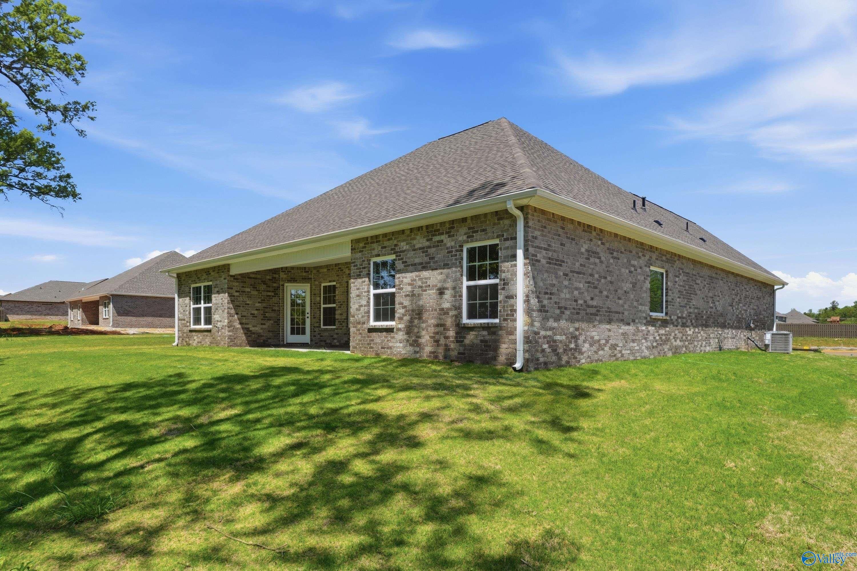 Brick single-story home with covered patio, large windows, brick exterior, and lush green yard in The Meadows, Athens, Alabama