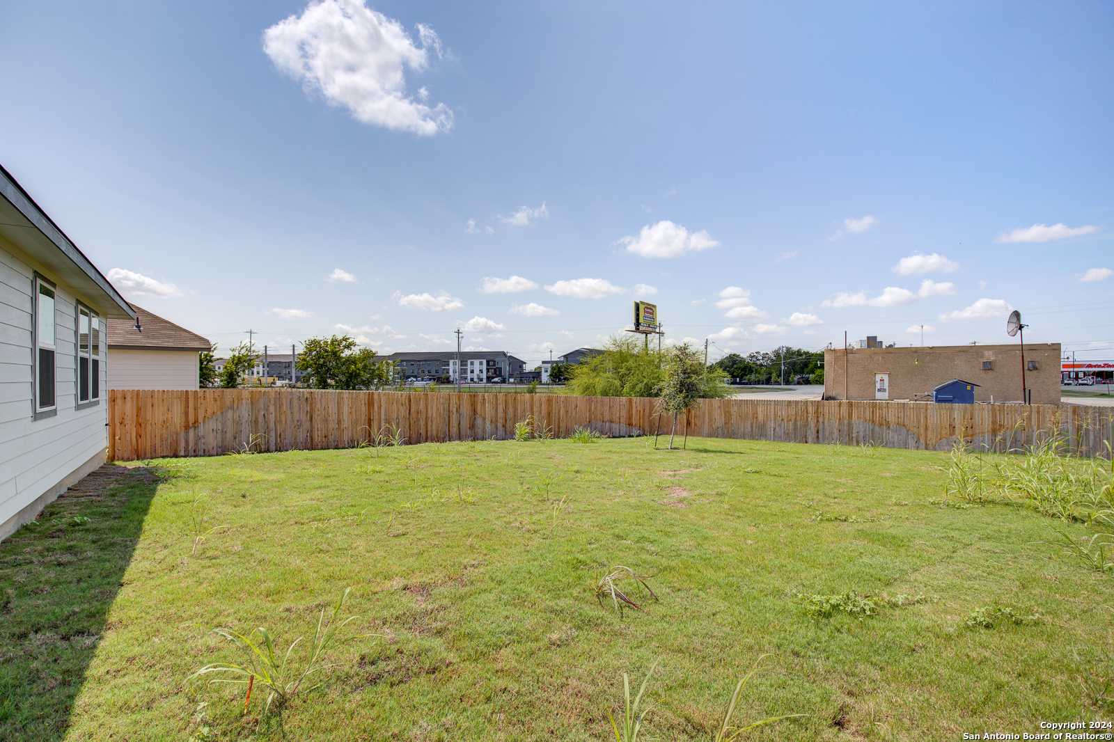 Expansive grassy backyard with wooden privacy fence beside single-story home in Davidson Homes The Daphne J, Seguin, Texas