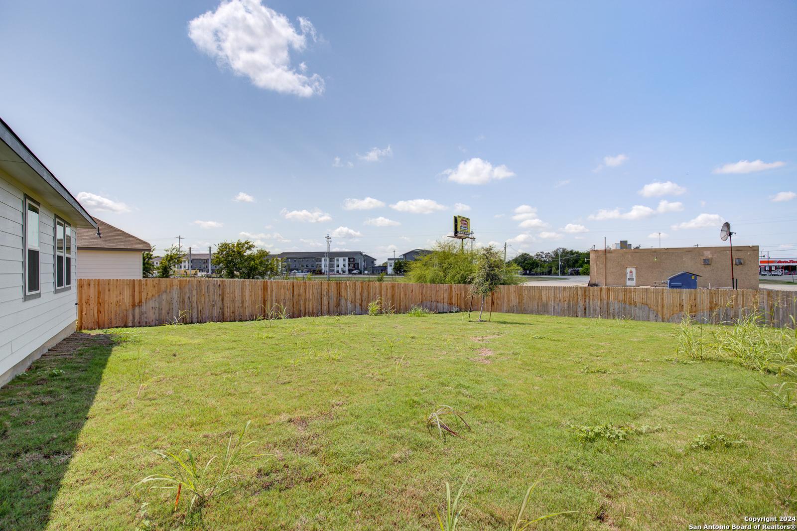 Expansive grassy backyard with wooden privacy fence beside single-story home in Davidson Homes The Daphne J, Seguin, Texas