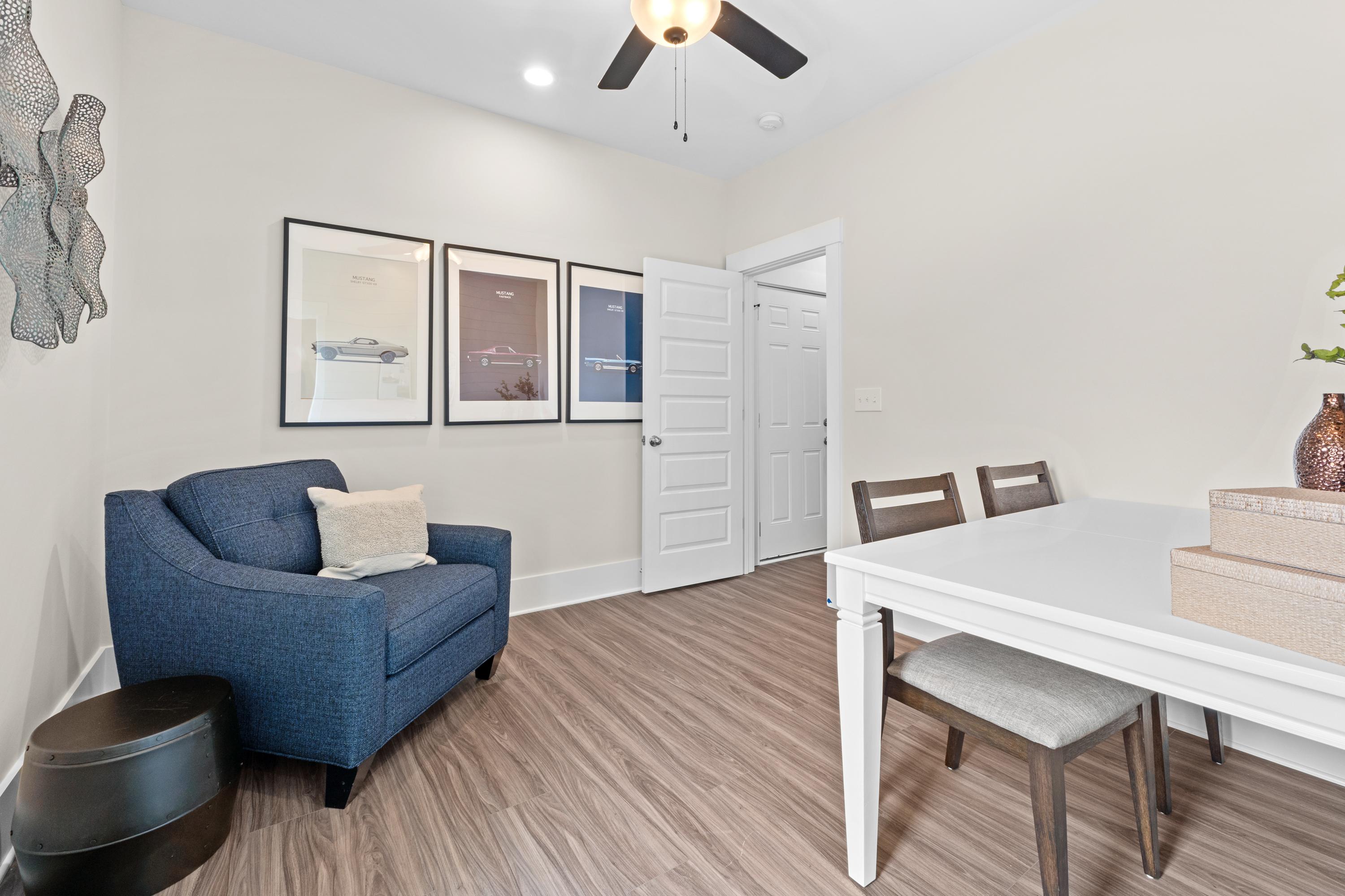 Cozy dining nook in Ivy Hills Toney Alabama by Davidson Homes with blue armchair white table hardwood floors and wall art