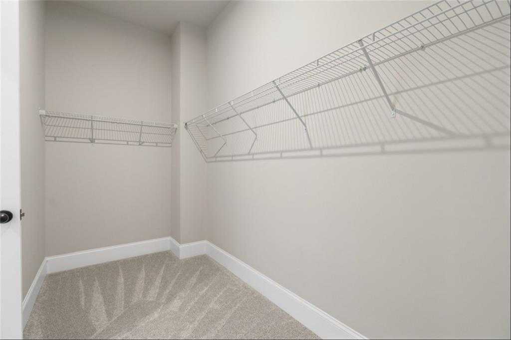 Spacious walk-in closet with wire shelving, beige walls, and carpeted floor in Davidson Homes The Seaside A, Woodstock, GA