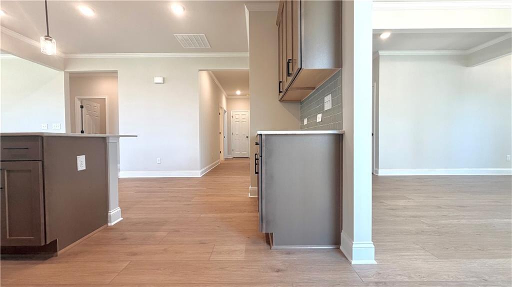 Open-concept kitchen with wood flooring and view of living area in The Glenwood A floor plan at Wehunt Meadows, Hoschton.