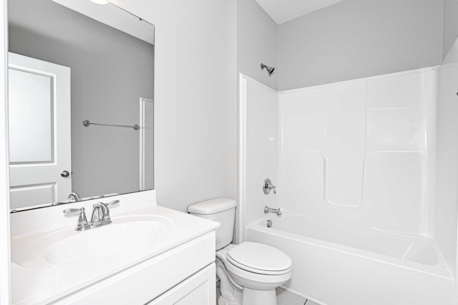 Spacious master bathroom in The Montgomery home with white vanity, large mirror, toilet, and bathtub-shower combo