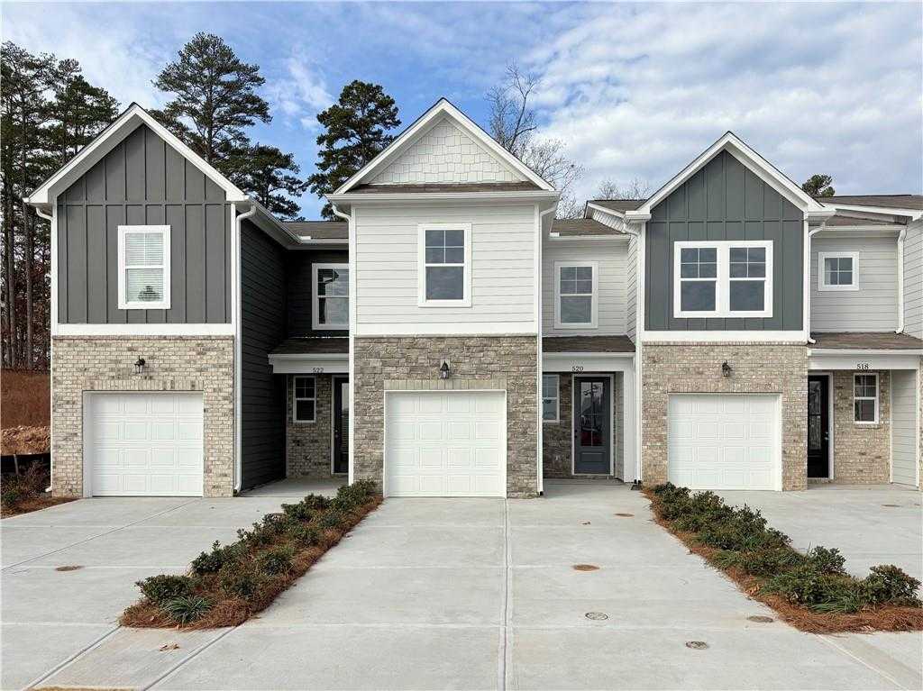 Three 2-story townhomes with gray siding, brick bases, garages, and landscaped driveways in Stegall Village, Emerson, Georgia Davidson Homes Wilmington B