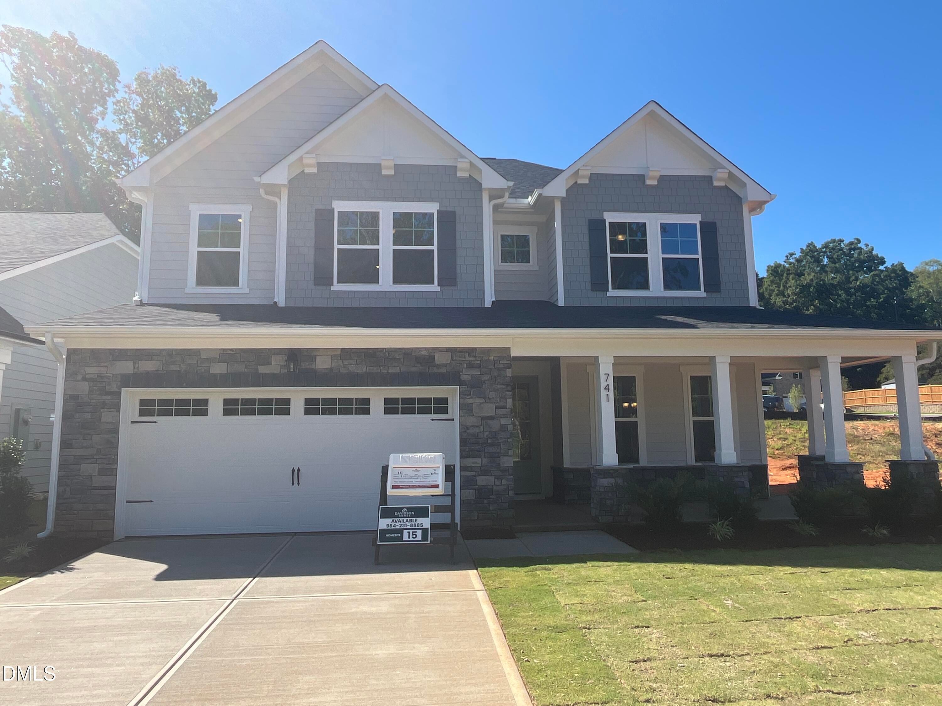 Two-story gray and stone new construction home with covered porch and 2-car garage at Sage on North Main, Wake Forest, NC.