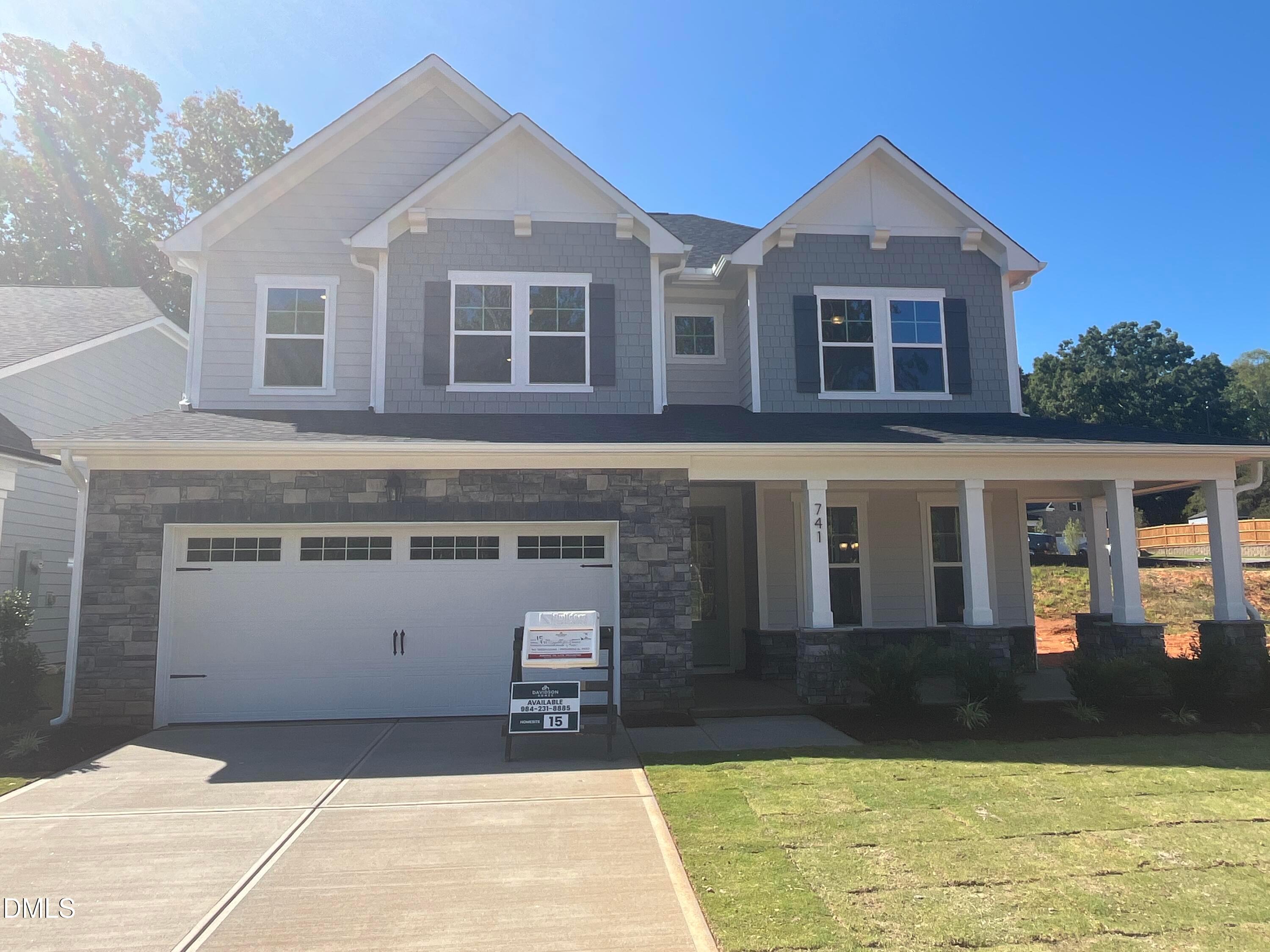Two-story gray and stone new construction home with covered porch and 2-car garage at Sage on North Main, Wake Forest, NC.