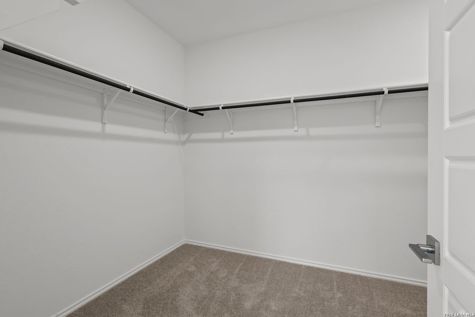 Spacious walk-in closet with black shelving and beige carpet in master suite, Davidson Homes The Sequoia B, San Antonio, Texas