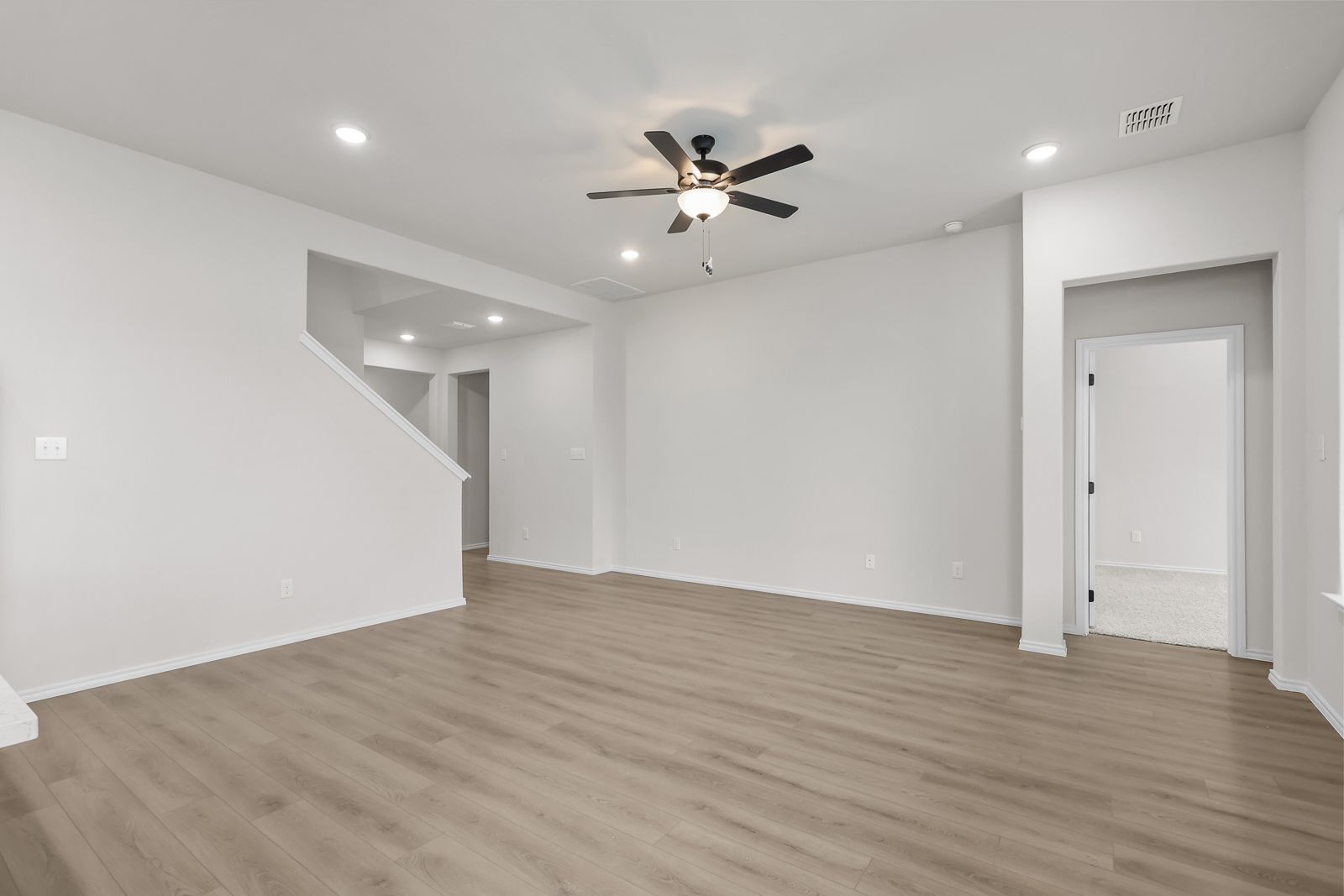 Spacious open-concept living area in The Sequoia C featuring modern wood-look flooring and a central ceiling fan.