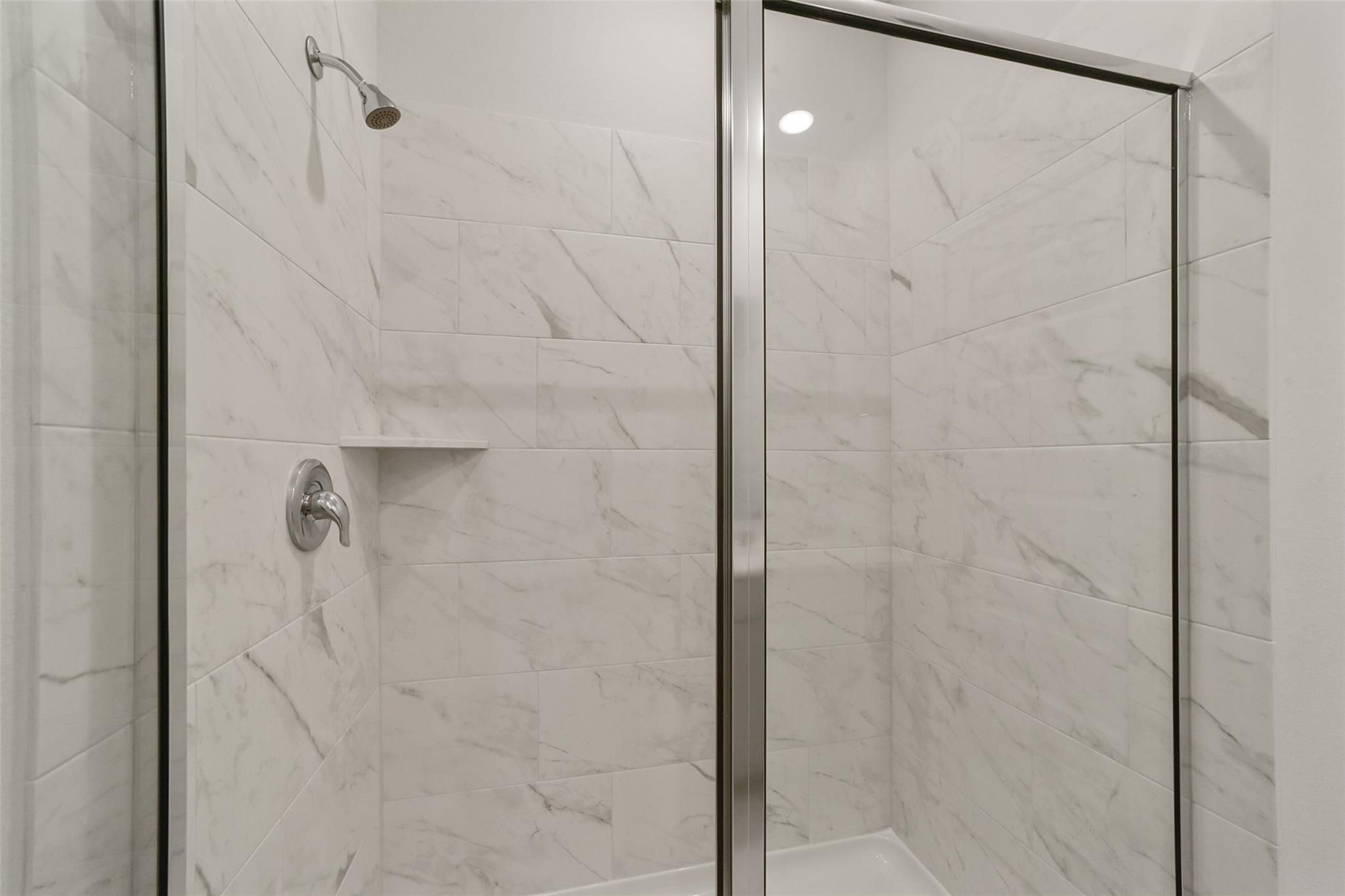 Elegant frameless glass shower with white subway tile in master bath of Davidson Homes San Marcos E, Beasley, Texas