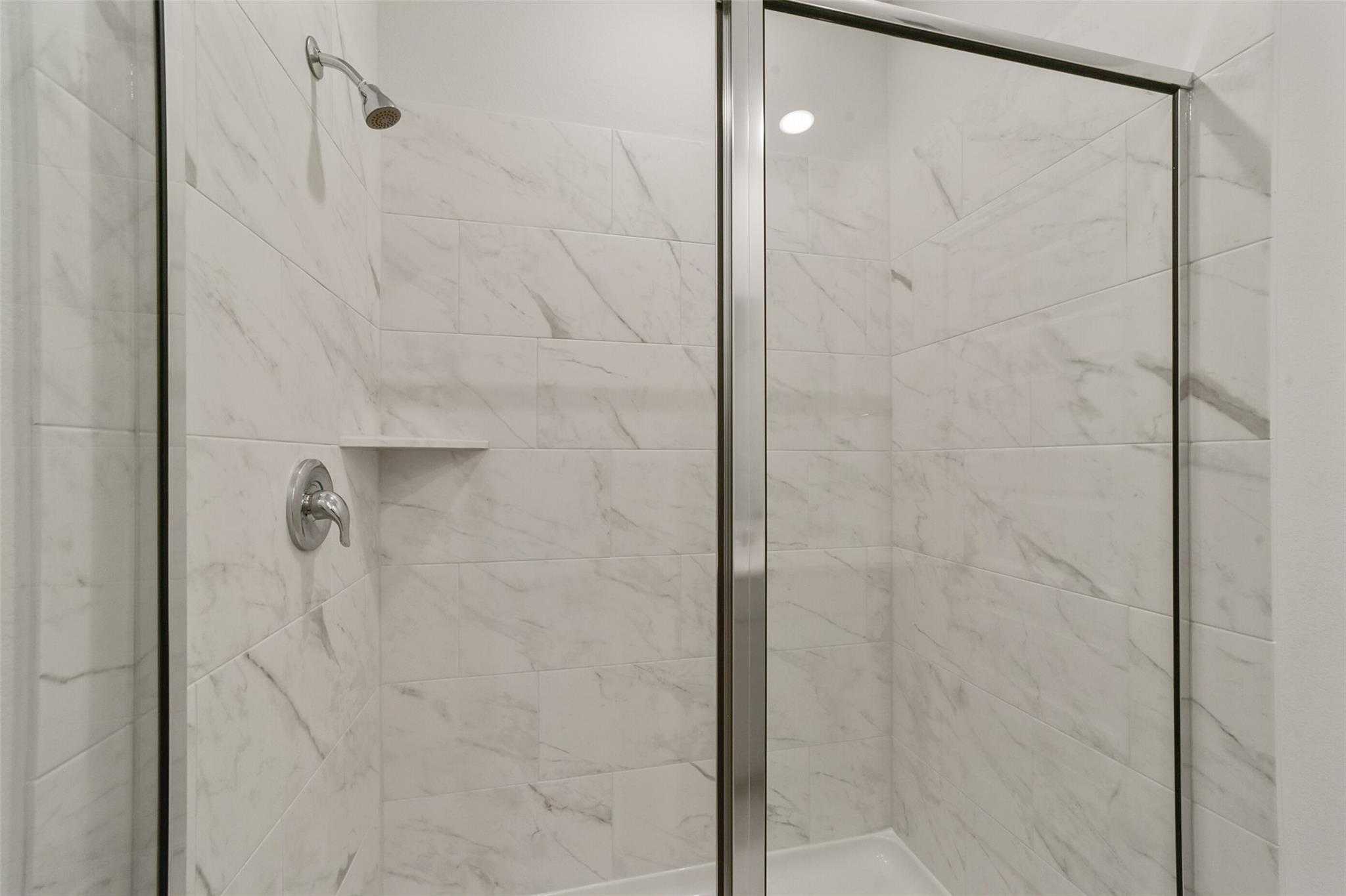 Elegant frameless glass shower with white subway tile in master bath of Davidson Homes San Marcos E, Beasley, Texas