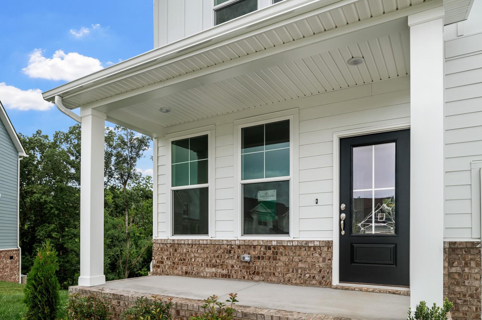 Covered front porch with brick base and black front door at The Logan C home in Calista Farms, White House, Tennessee.