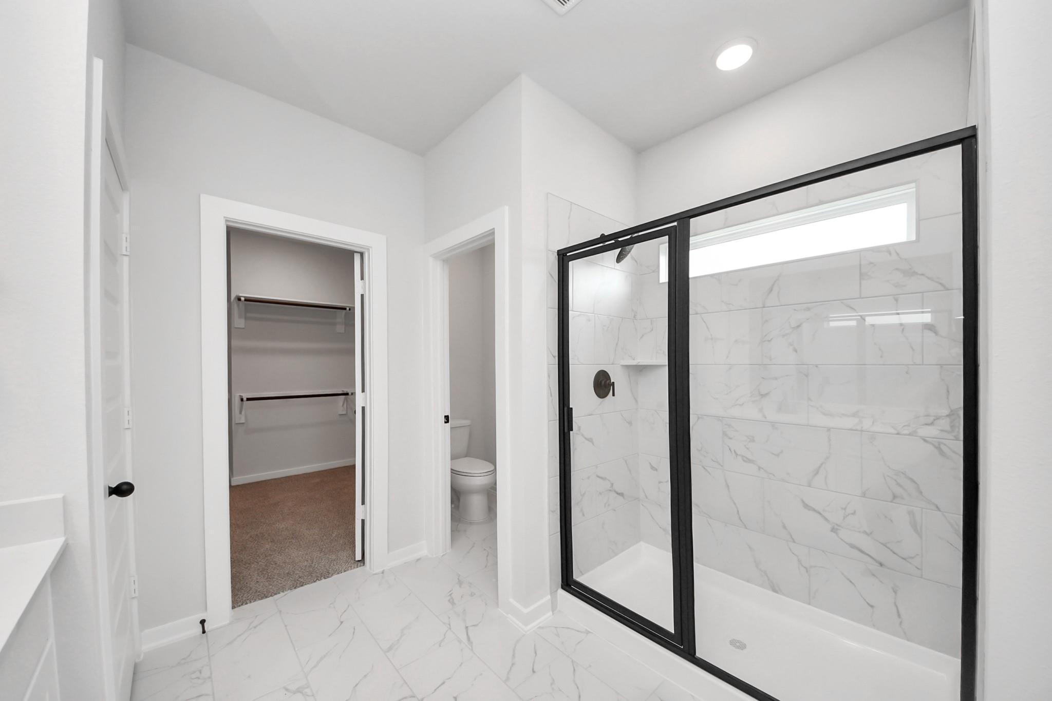 Modern bathroom with marble-style walk-in shower, private water closet, and walk-in closet in Davidson Homes Everett C plan.