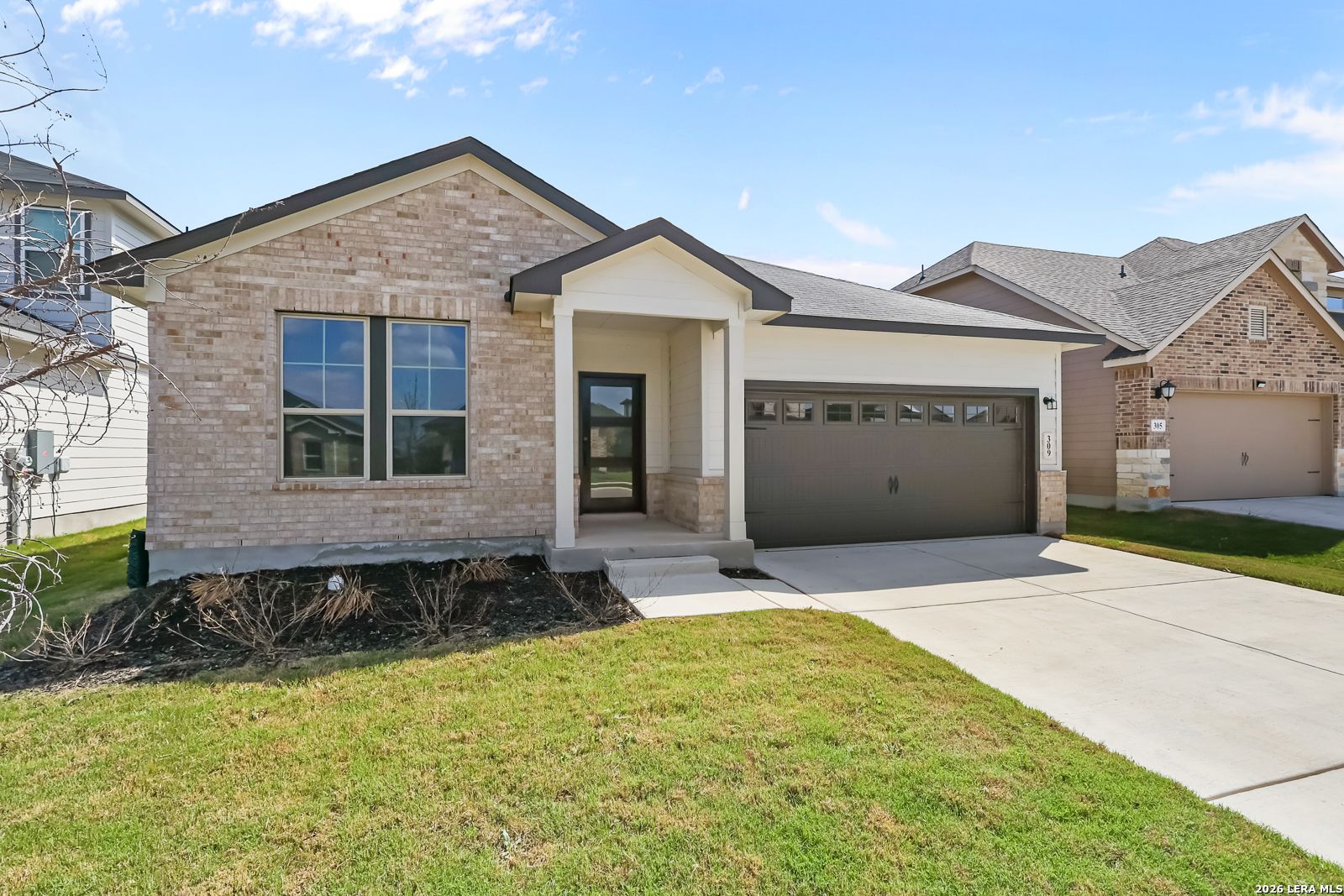 Modern beige brick single-story home with 2-car garage, covered porch, and lush front yard in Hannah Heights, Seguin, Texas