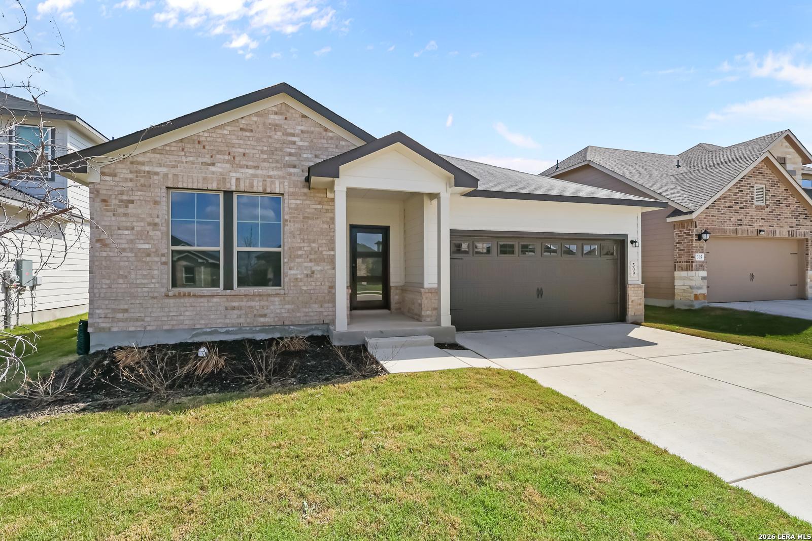 Modern beige brick single-story home with 2-car garage, covered porch, and lush front yard in Hannah Heights, Seguin, Texas