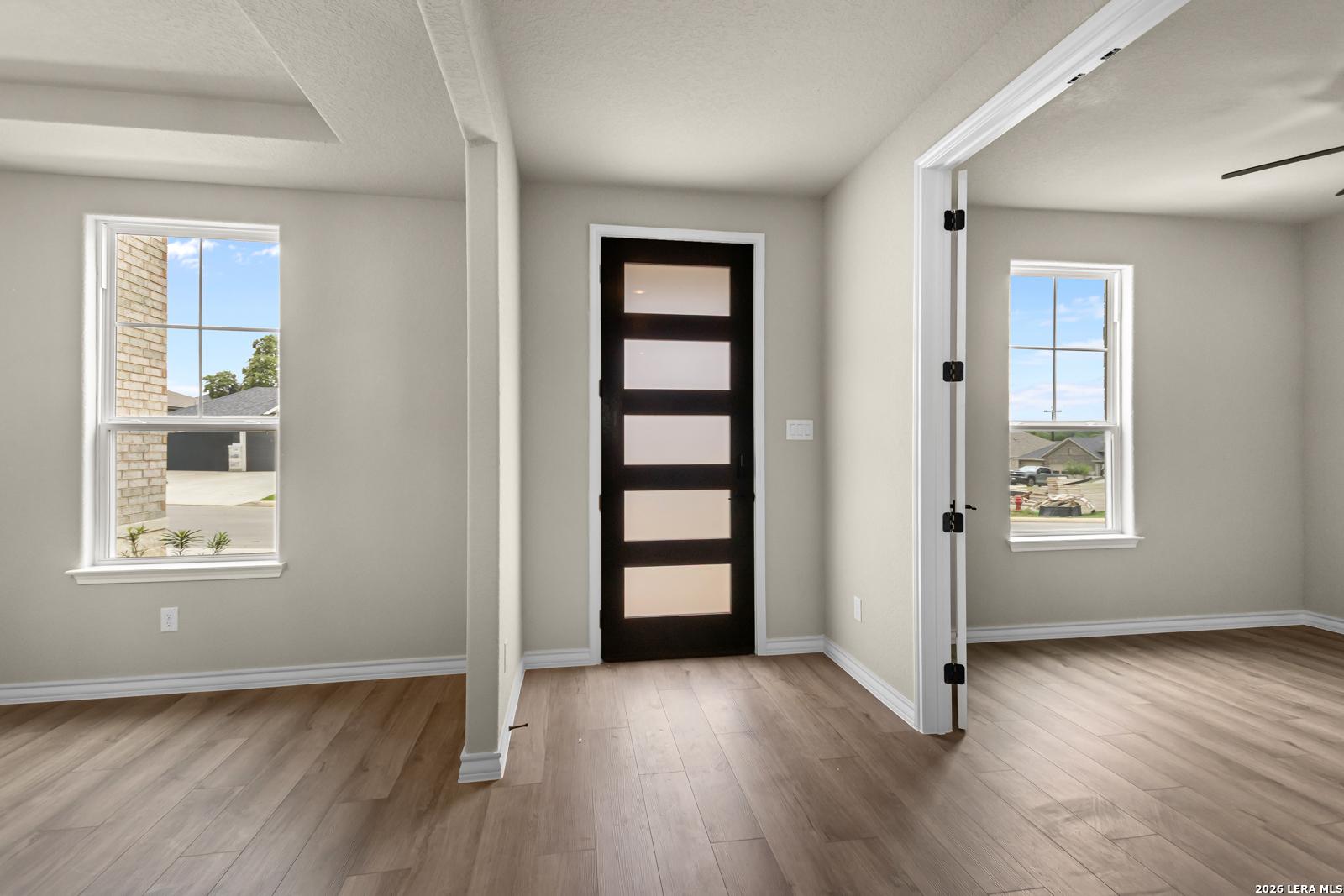 Modern office or bedroom with wood-look flooring and dark contemporary door in Davidson Homes Danbury H, Castroville, TX.