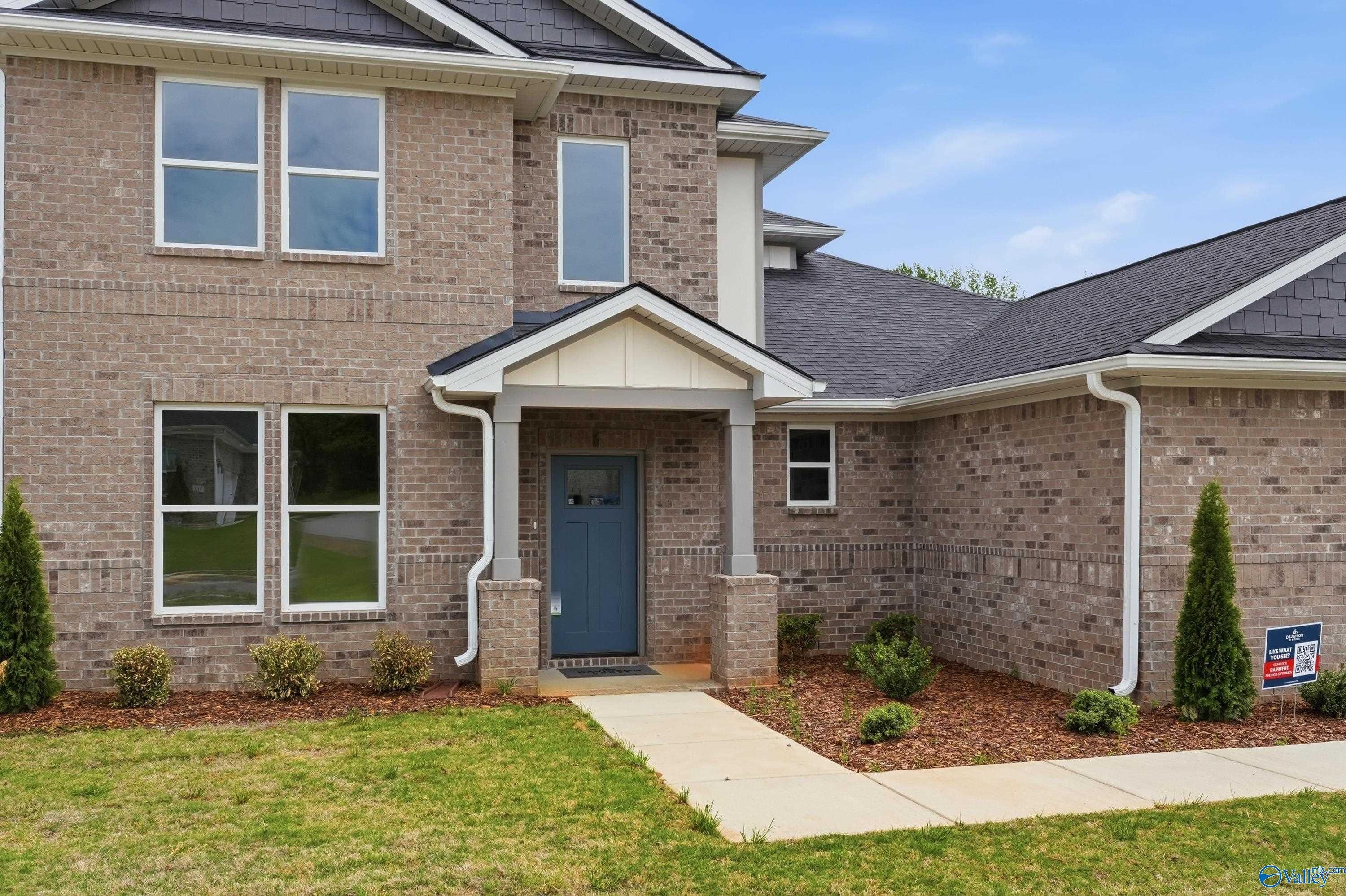 Two-story brick Dorado home by Davidson Homes in Riverton Preserve, Huntsville, Alabama, with blue front door, covered porch, and landscaped yard