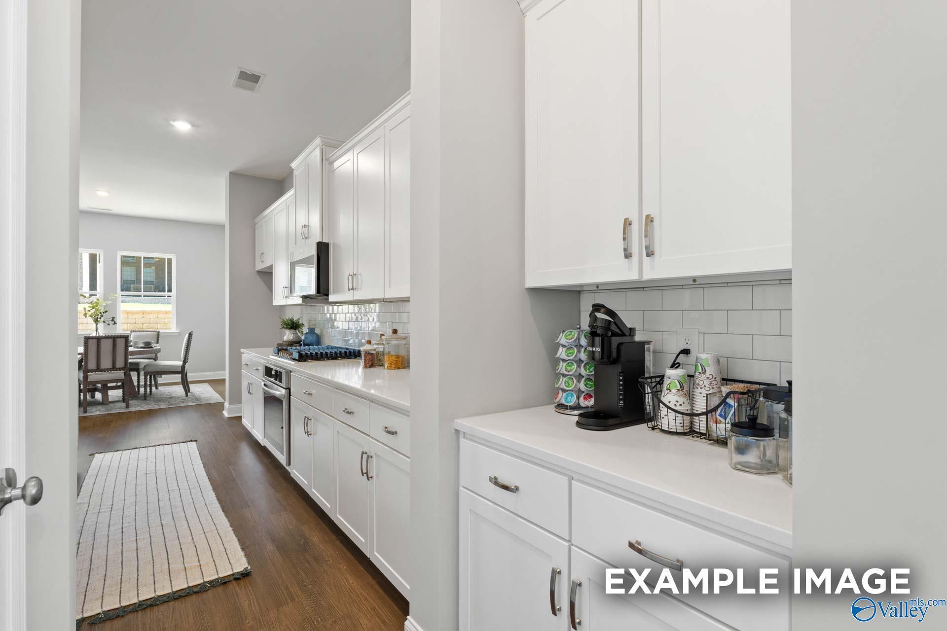 Modern white kitchen with quartz counters, subway tile backsplash, Keurig station in Evermore Homes The Haven E, Owens Cross Roads, AL