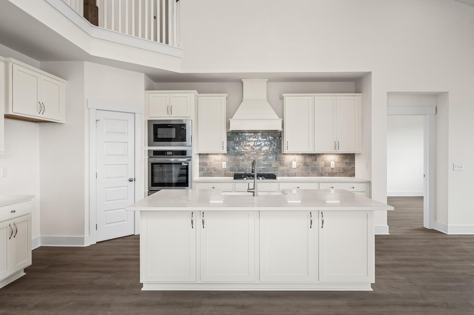 Modern white kitchen with large island and tile backsplash in The Ridgeport D floor plan by Davidson Homes in Mt. Juliet.