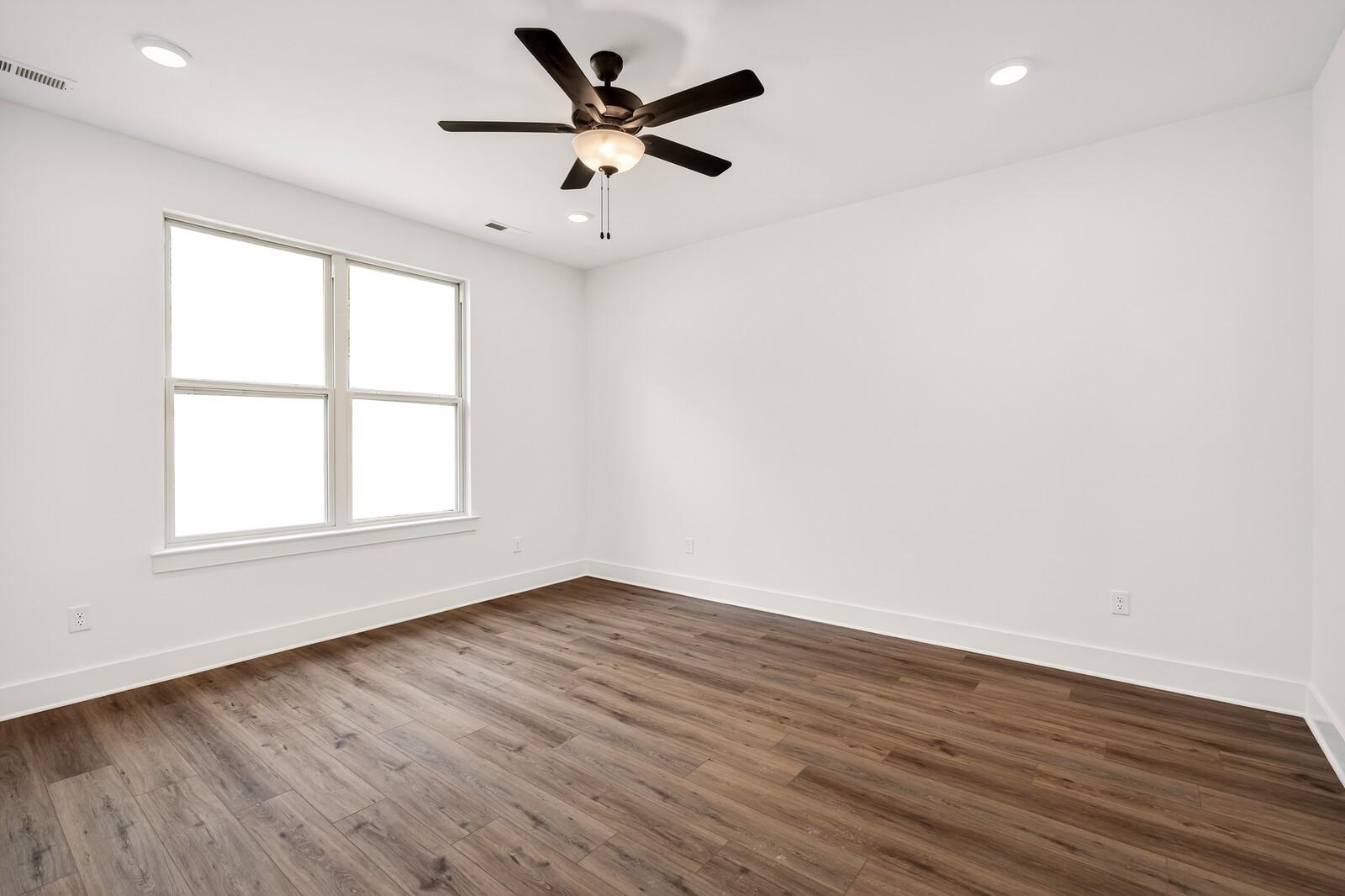 Bright empty bedroom with hardwood floors, ceiling fan, large window in Davidson Homes Ridgeport C, Gallatin, TN