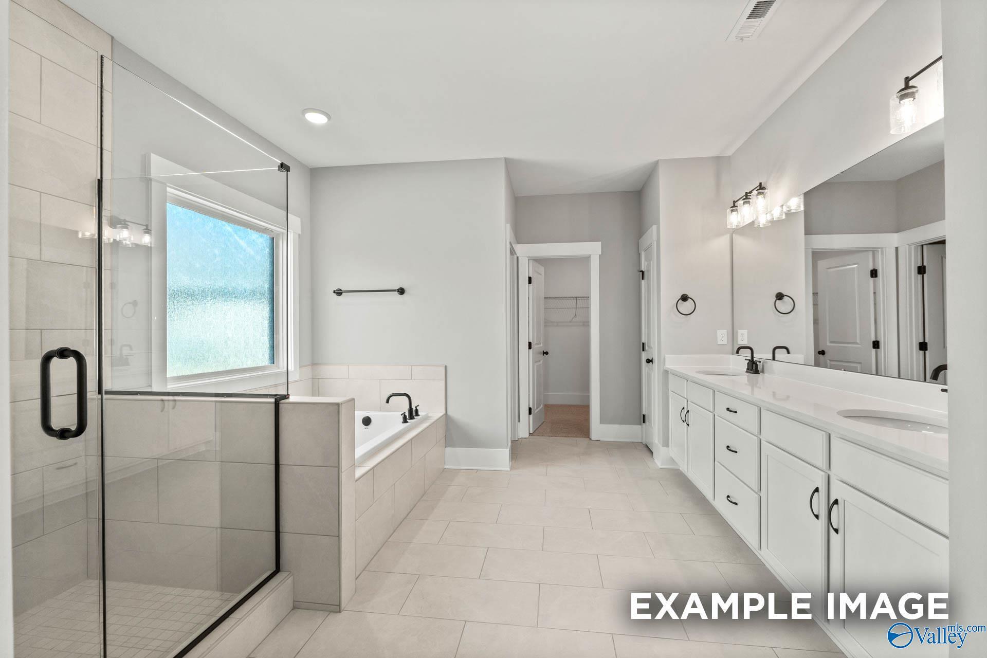 Modern primary bathroom with dual vanity, soaking tub, and glass shower in The Finleigh floor plan, Briercreek, Meridianville.