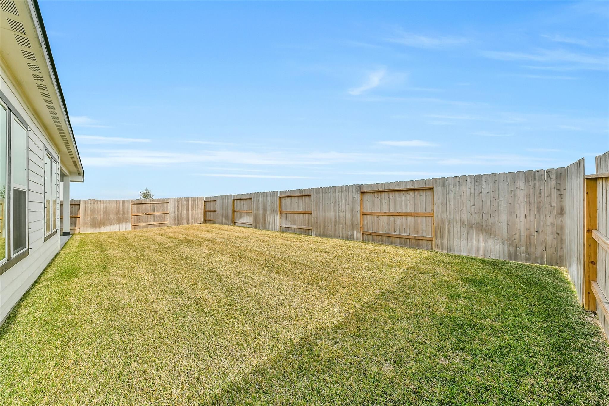 Expansive grassy backyard enclosed by wooden privacy fence in Davidson Homes The George A, 4-bedroom home, Lago Mar, Texas City, Texas