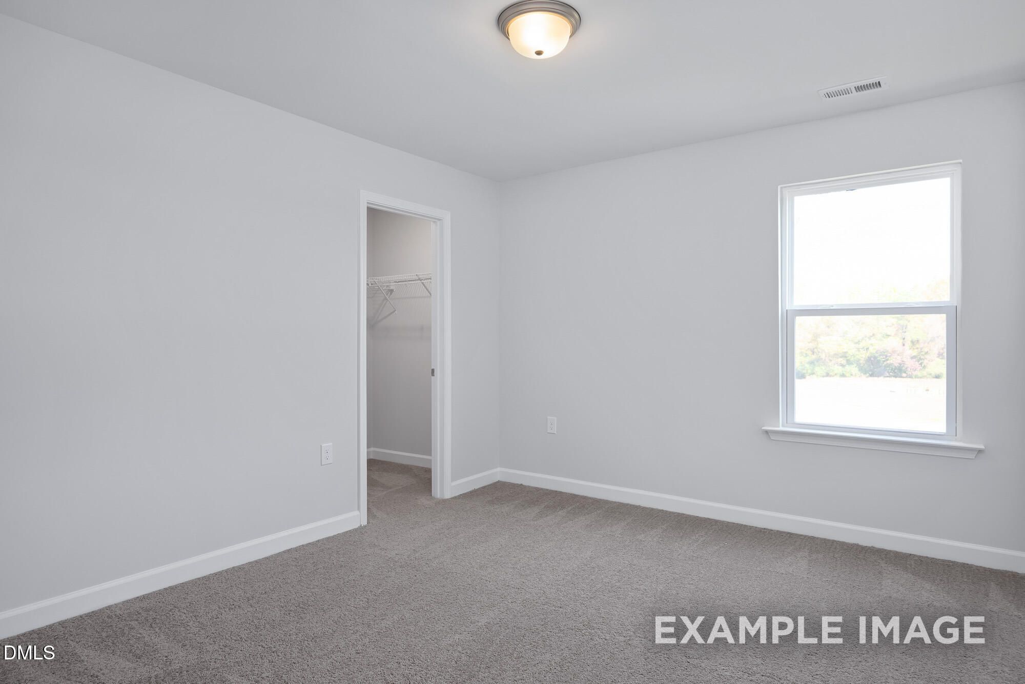 Bright secondary bedroom with white walls, walk-in closet, large window, and carpet in The Hickory II B, Lillington, NC