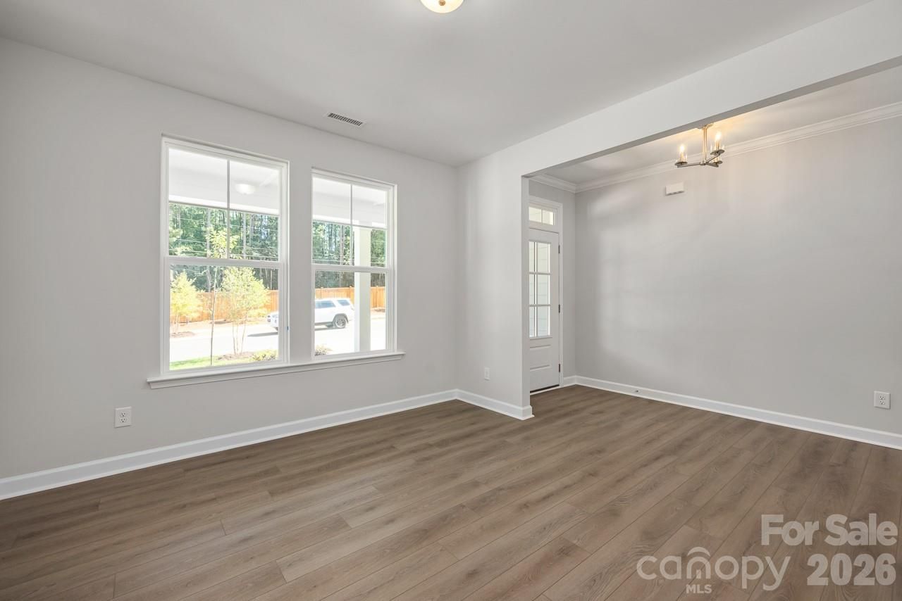 Bright open-concept living room with luxury vinyl plank floors and large windows in Davidson Homes Aspen B, Enclave at Belmont, NC