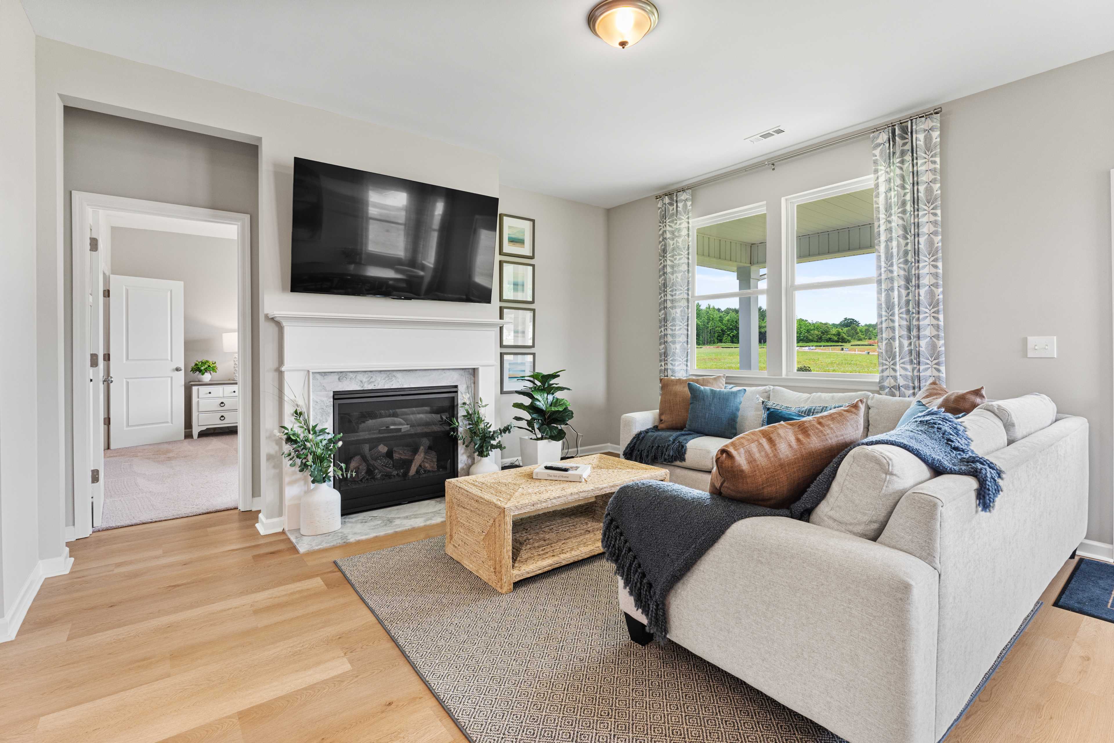 Cozy living room in Forest Glen Hazel Green Alabama with gas fireplace, gray sectional sofa, hardwood floors and large windows