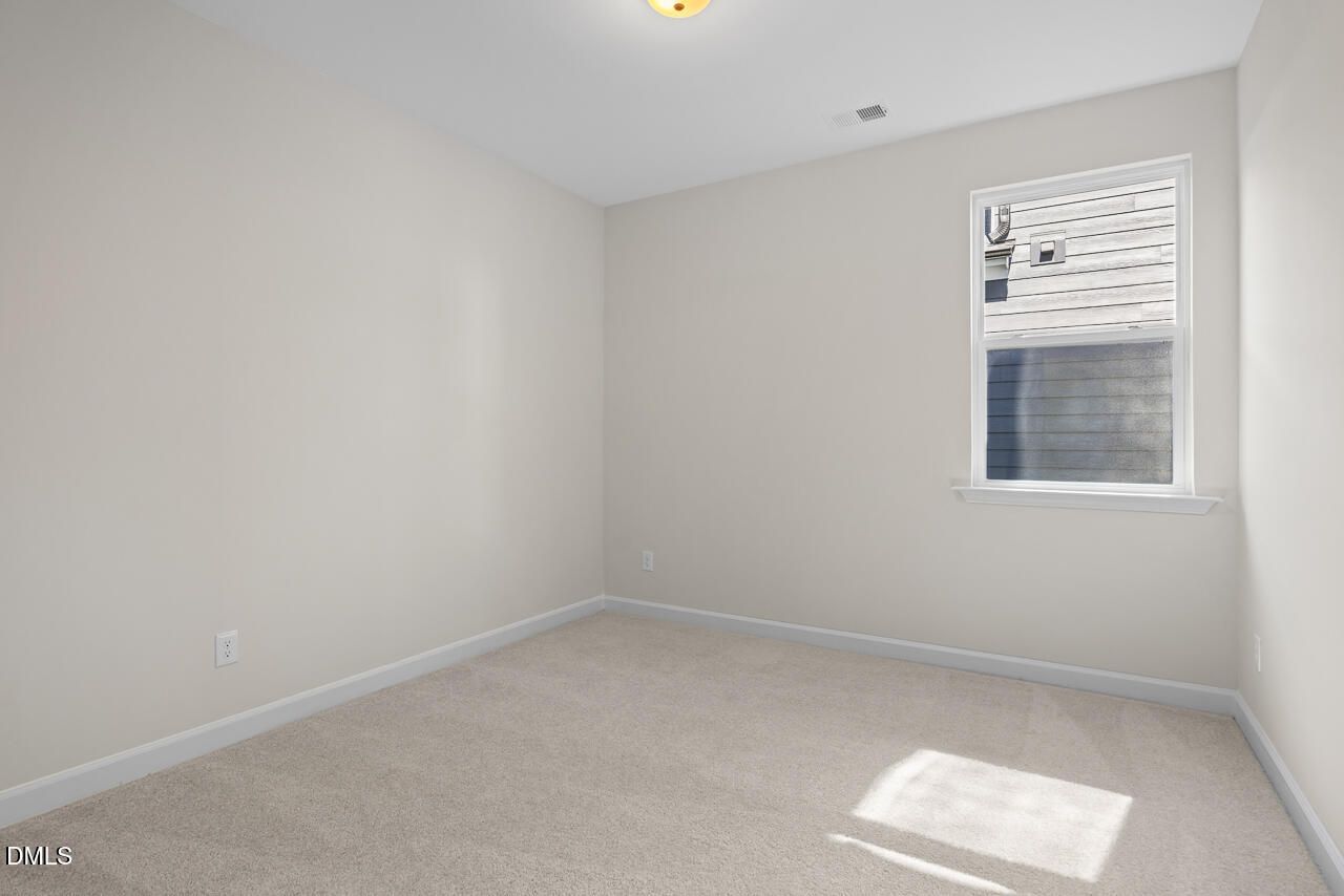 Bright empty bedroom with beige carpet, neutral walls, and single window in Davidson Homes The Preston B, Wendell Ridge, NC