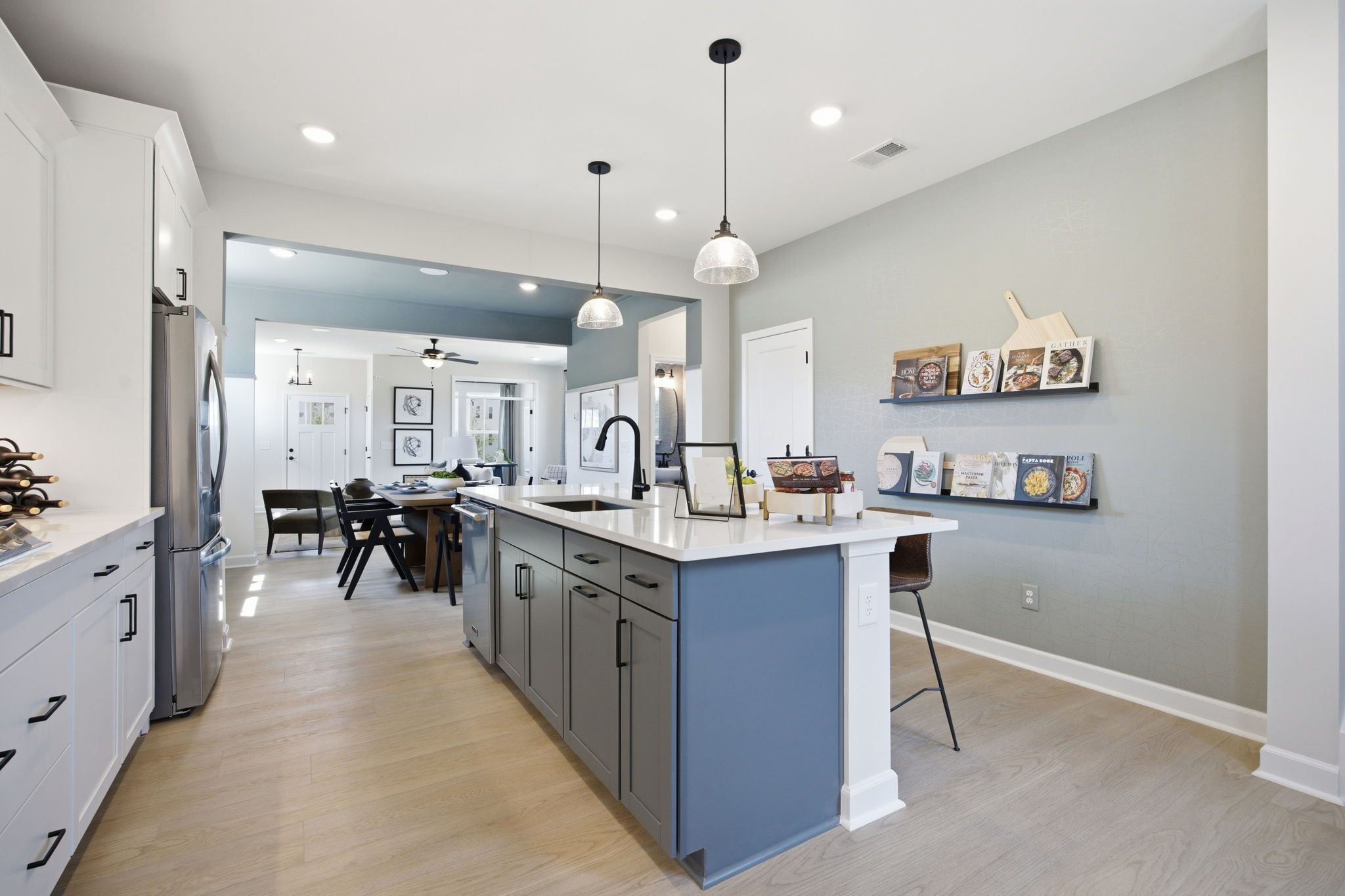 Modern kitchen in The Burke C design featuring a large blue island, white cabinets, and open-concept dining area.