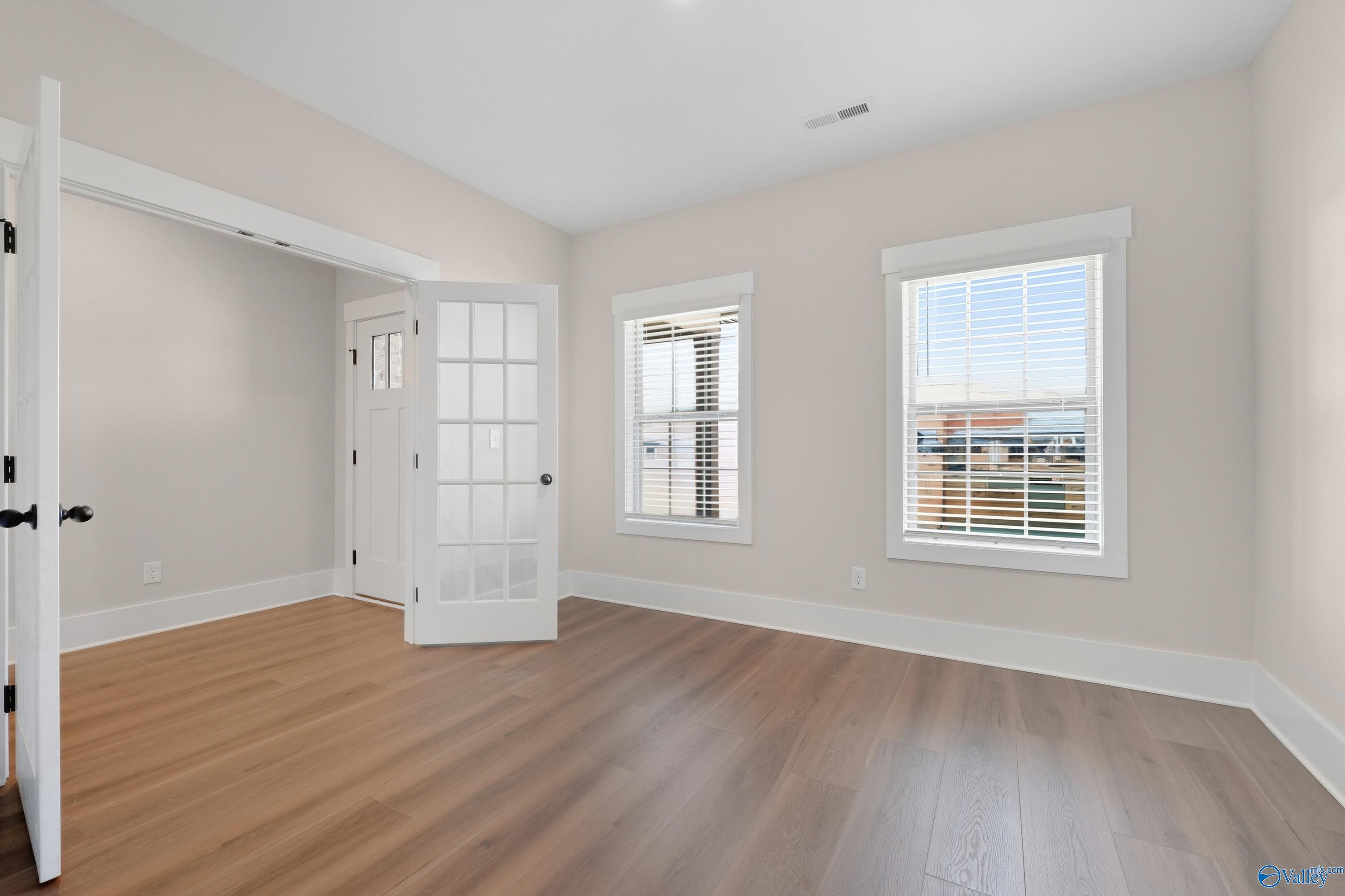 Bright bedroom with soft pink walls, hardwood floors, French doors, and large windows in Davidson Homes The Shelby A, Athens AL