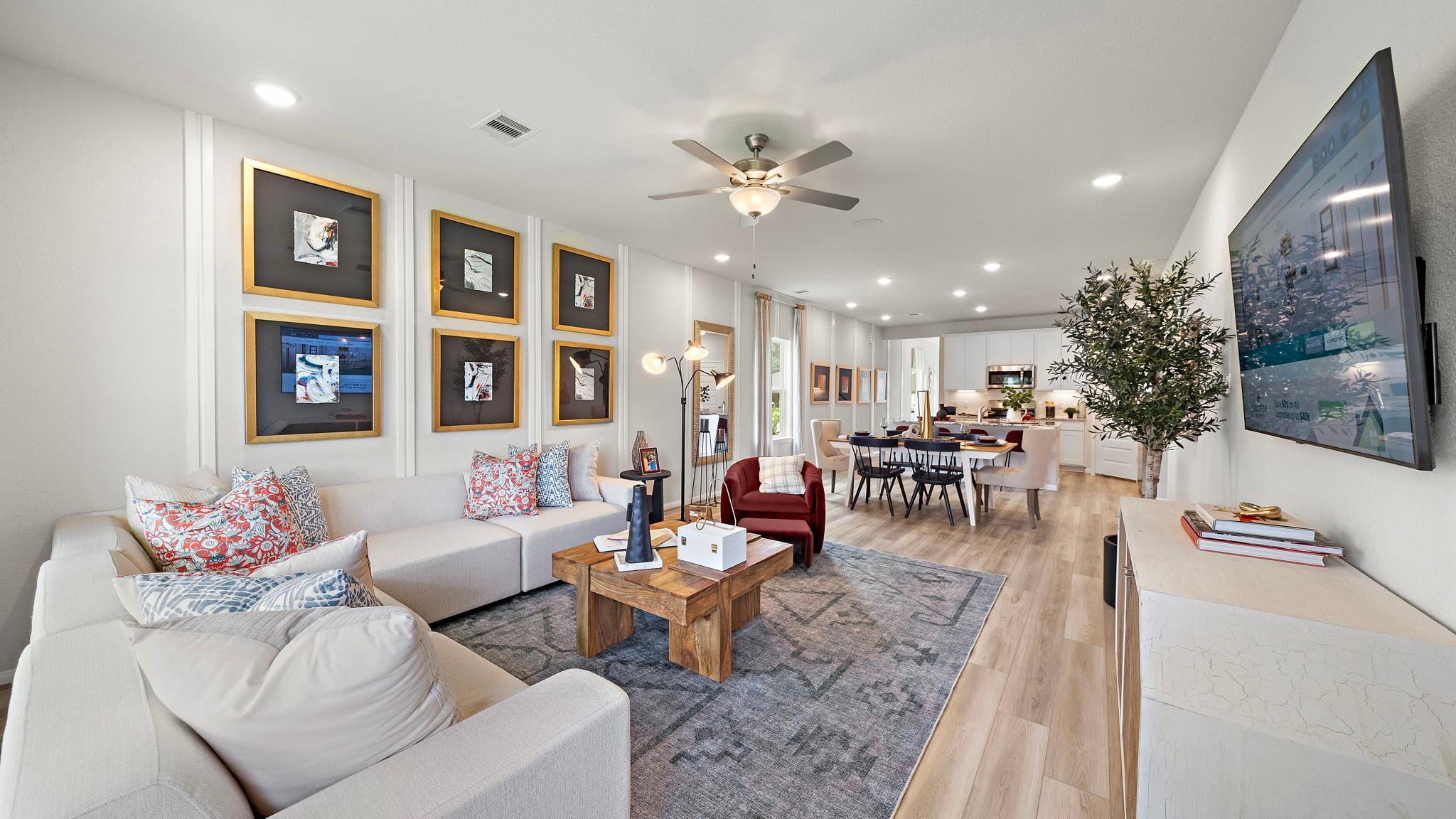 Spacious open-concept living and dining room at Liberty Estates in Cleveland Texas with white sectional sofa, wooden coffee table, and ceiling fan