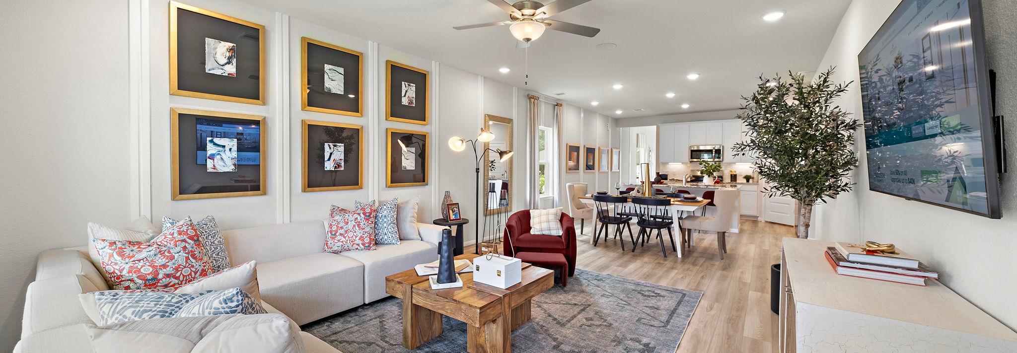 Spacious open-concept living and dining room at Liberty Estates in Cleveland Texas with white sectional sofa, wooden coffee table, and ceiling fan