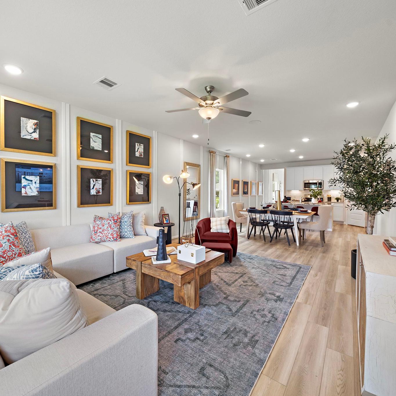Spacious open-concept living and dining room at Liberty Estates in Cleveland Texas with white sectional sofa, wooden coffee table, and ceiling fan