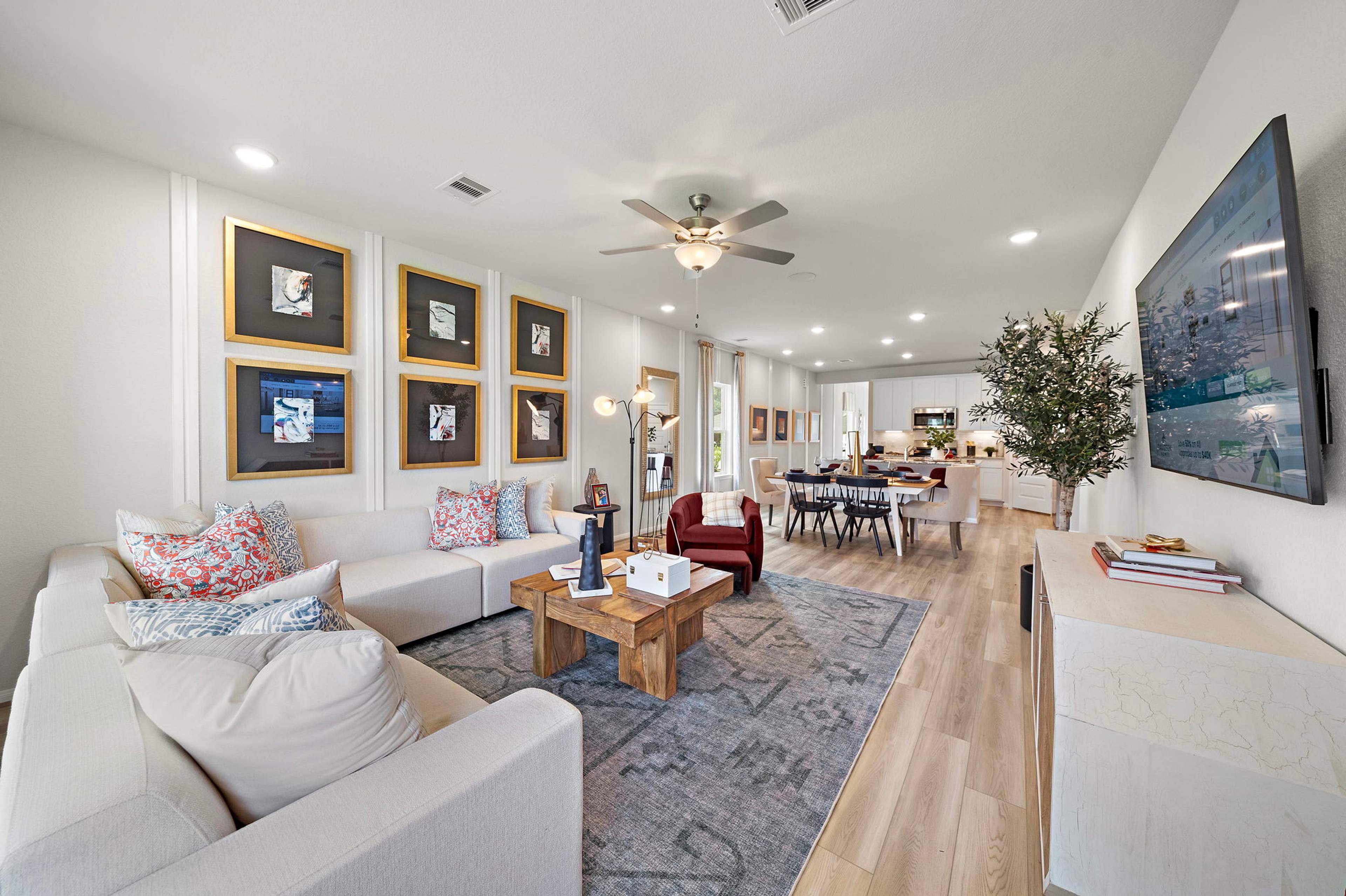 Spacious open-concept living and dining room at Liberty Estates in Cleveland Texas with white sectional sofa, wooden coffee table, and ceiling fan