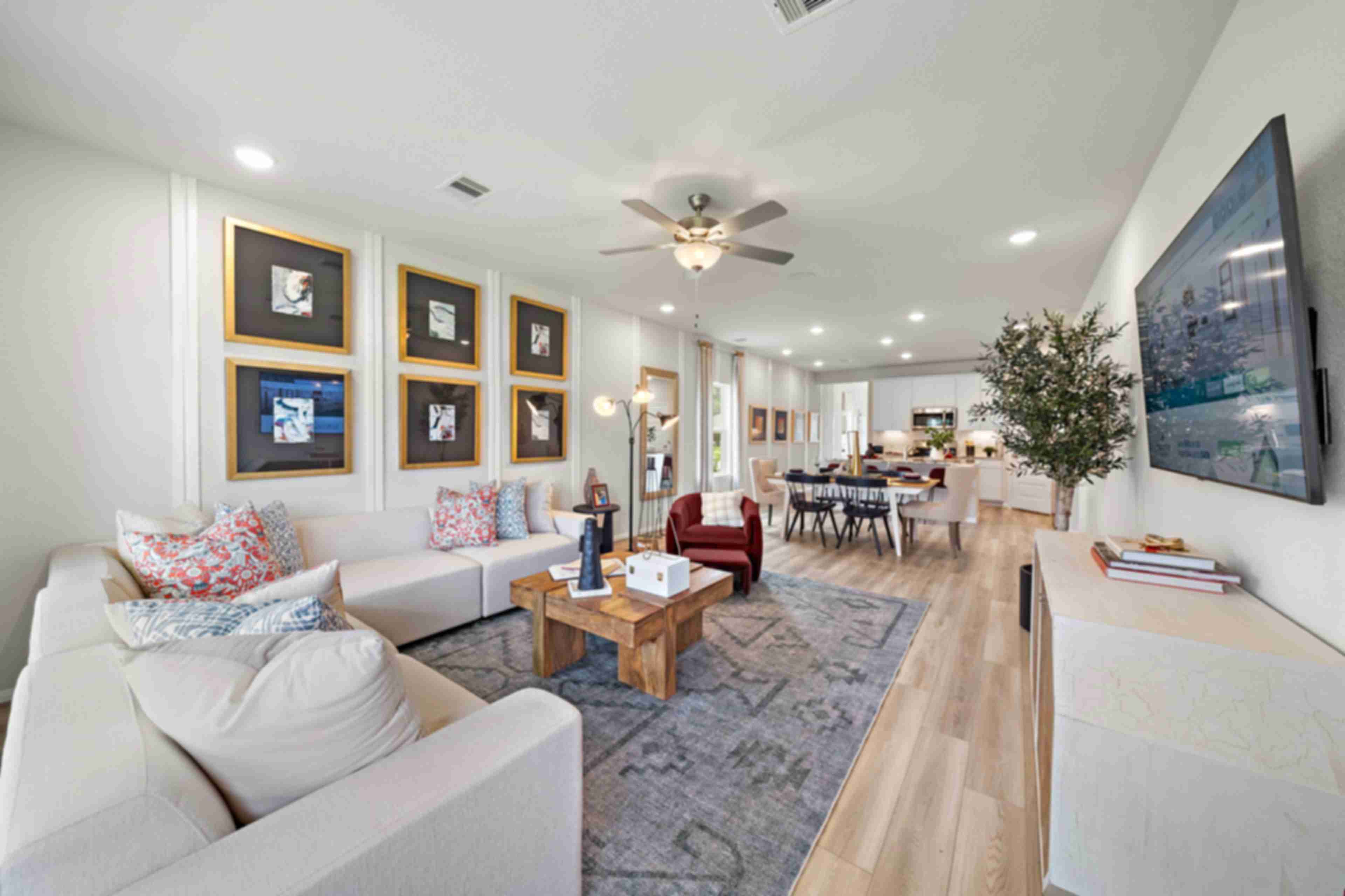 Spacious open-concept living and dining room at Liberty Estates in Cleveland Texas with white sectional sofa, wooden coffee table, and ceiling fan