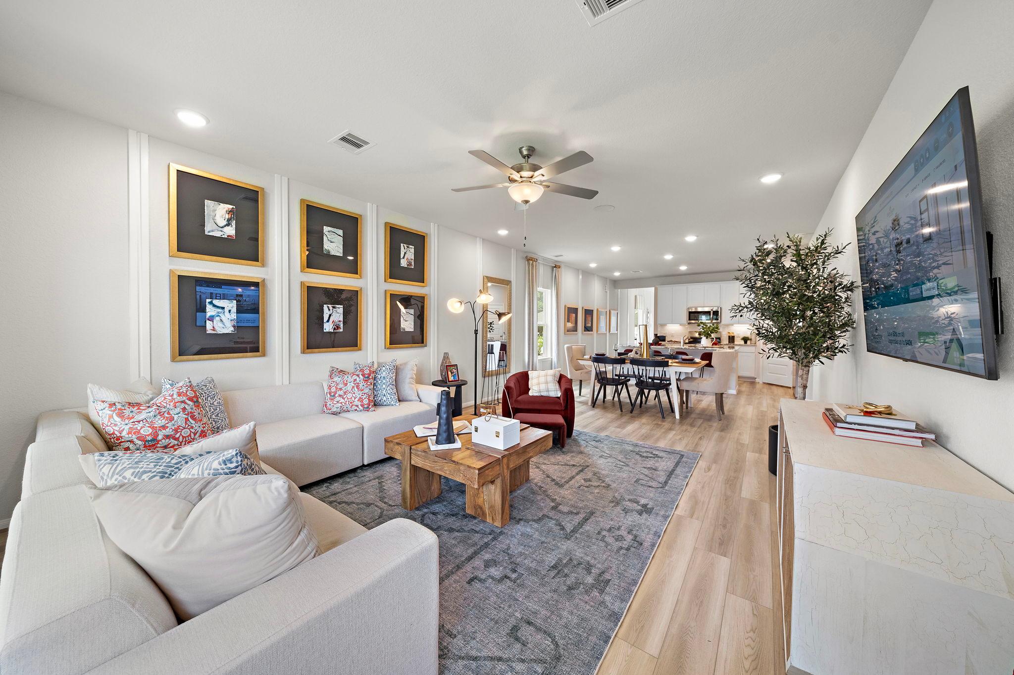 Open-concept living and dining room at Liberty Estates in Cleveland, Texas with white sectional sofa, wooden dining table, ceiling fan, and modern decor