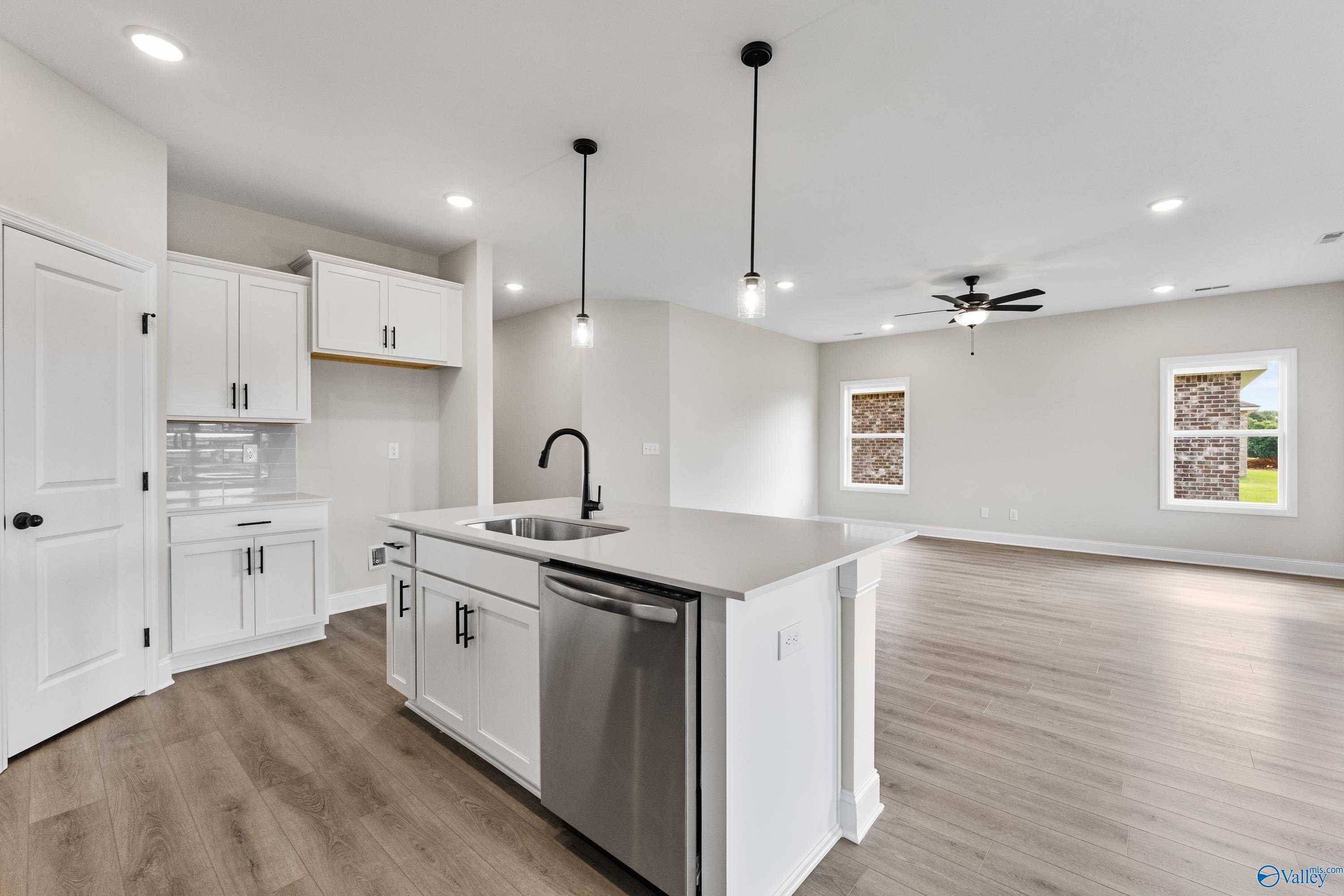 Modern open-concept kitchen with white shaker cabinets, island sink, stainless dishwasher in The Franklin B by Davidson Homes, Hazel Green, AL