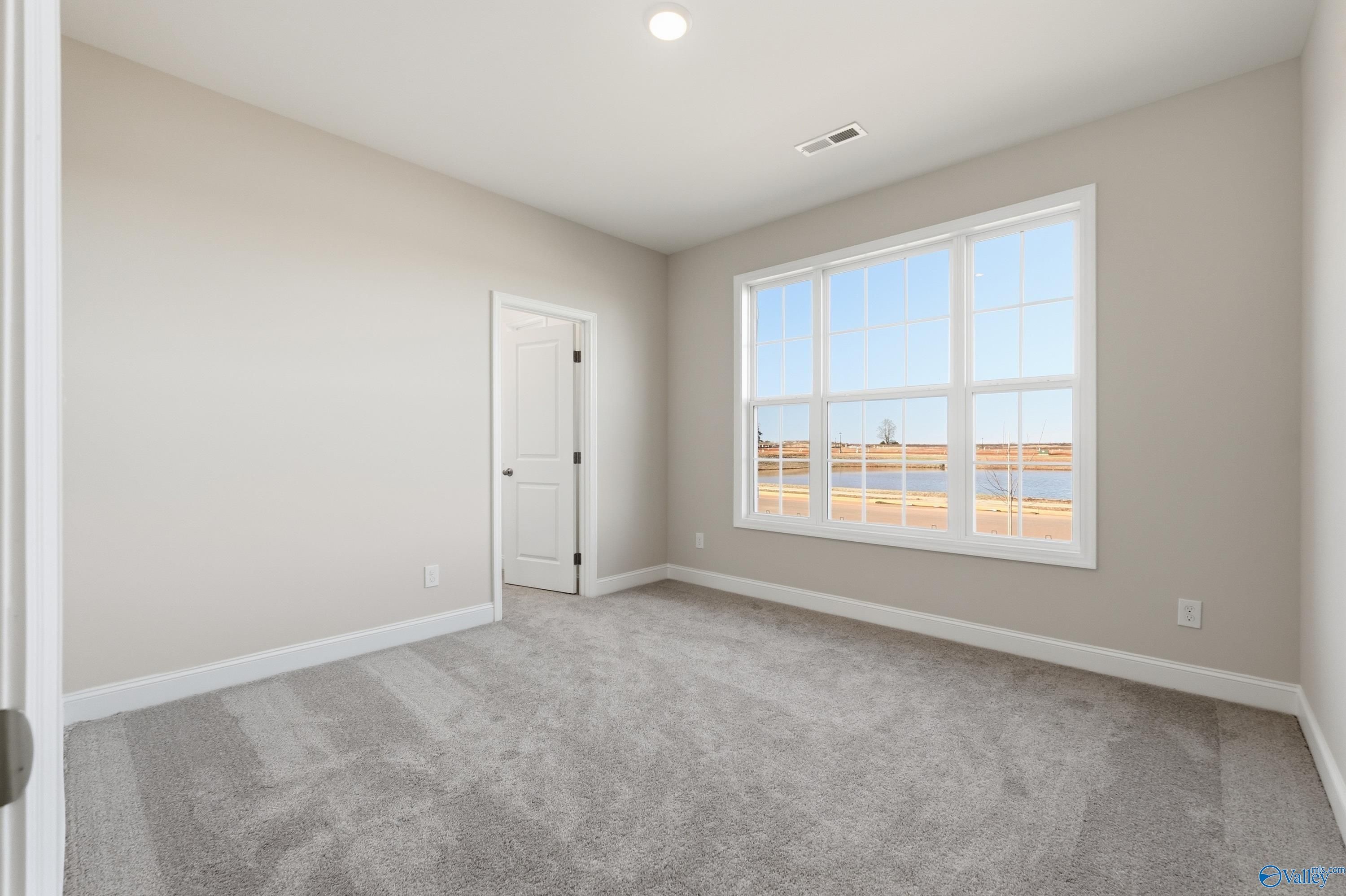 Bright secondary bedroom with large window overlooking serene lake in Davidson Homes The Montgomery B, Toney, Alabama