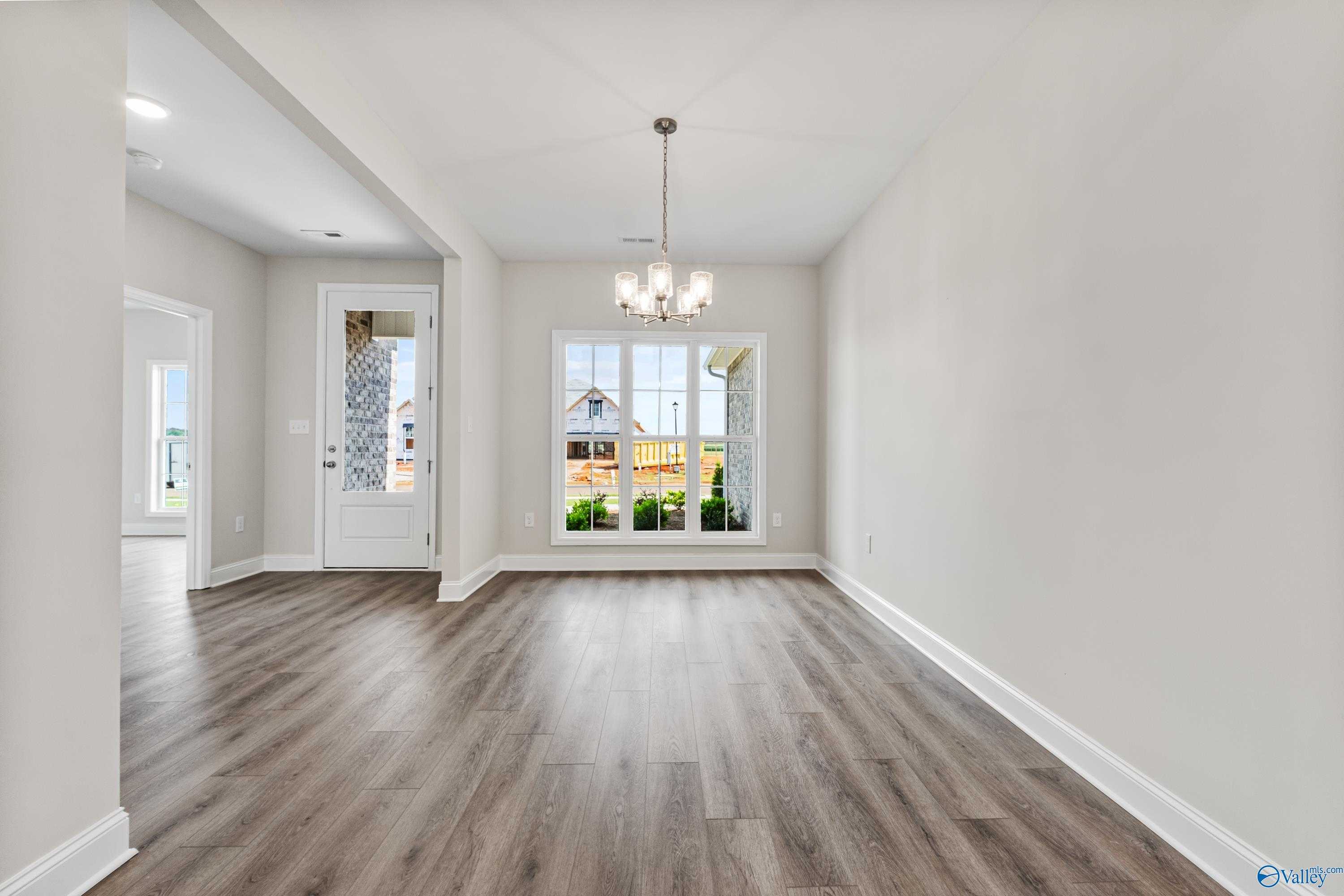 Bright dining room with chandelier, hardwood floors, and backyard window view in Davidson Homes The Finleigh, Toney, Alabama