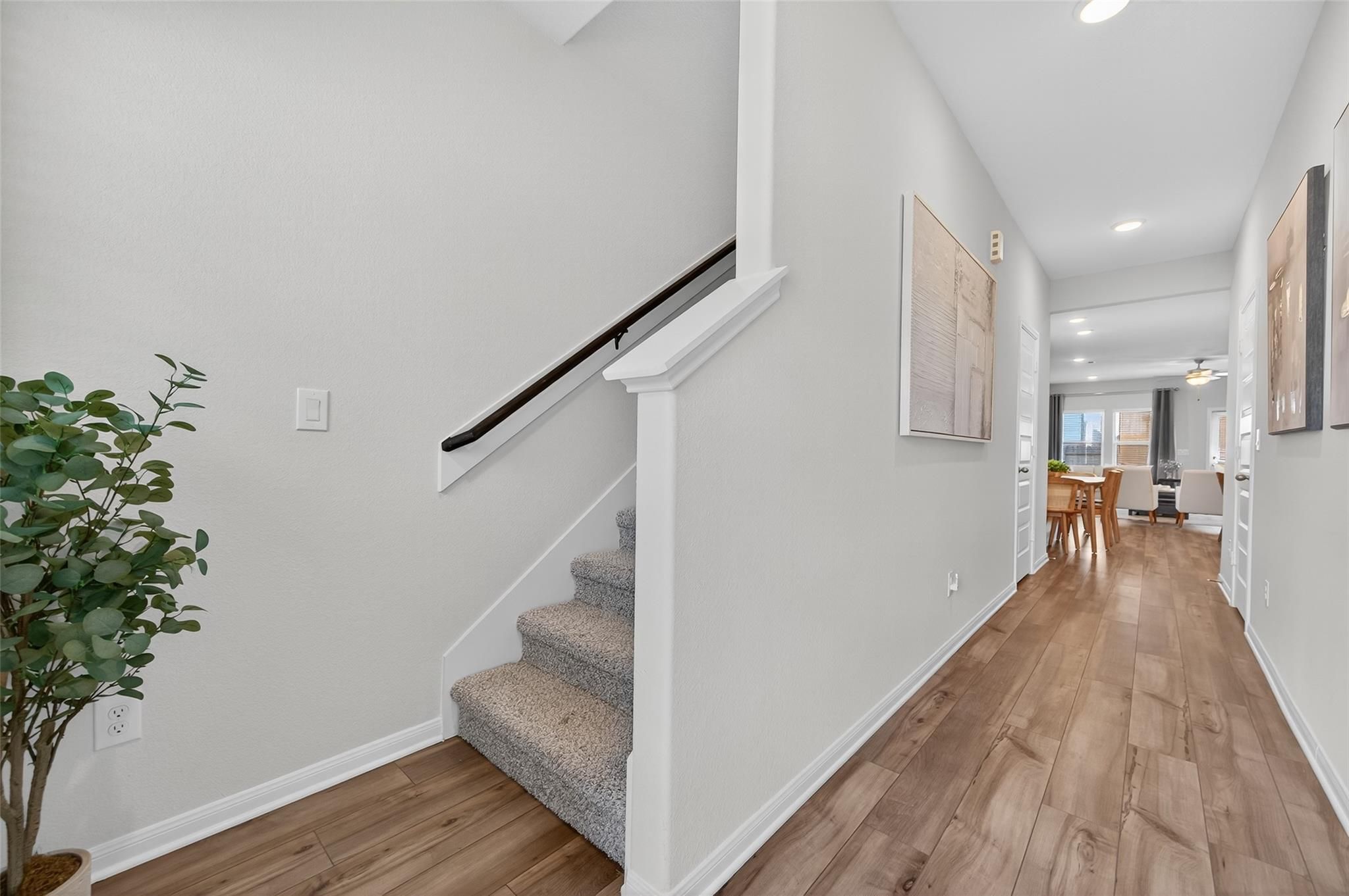 Bright hallway with light wood floors, carpeted staircase, potted plant and dining nook in Davidson Homes The Brazos E, Magnolia, Texas