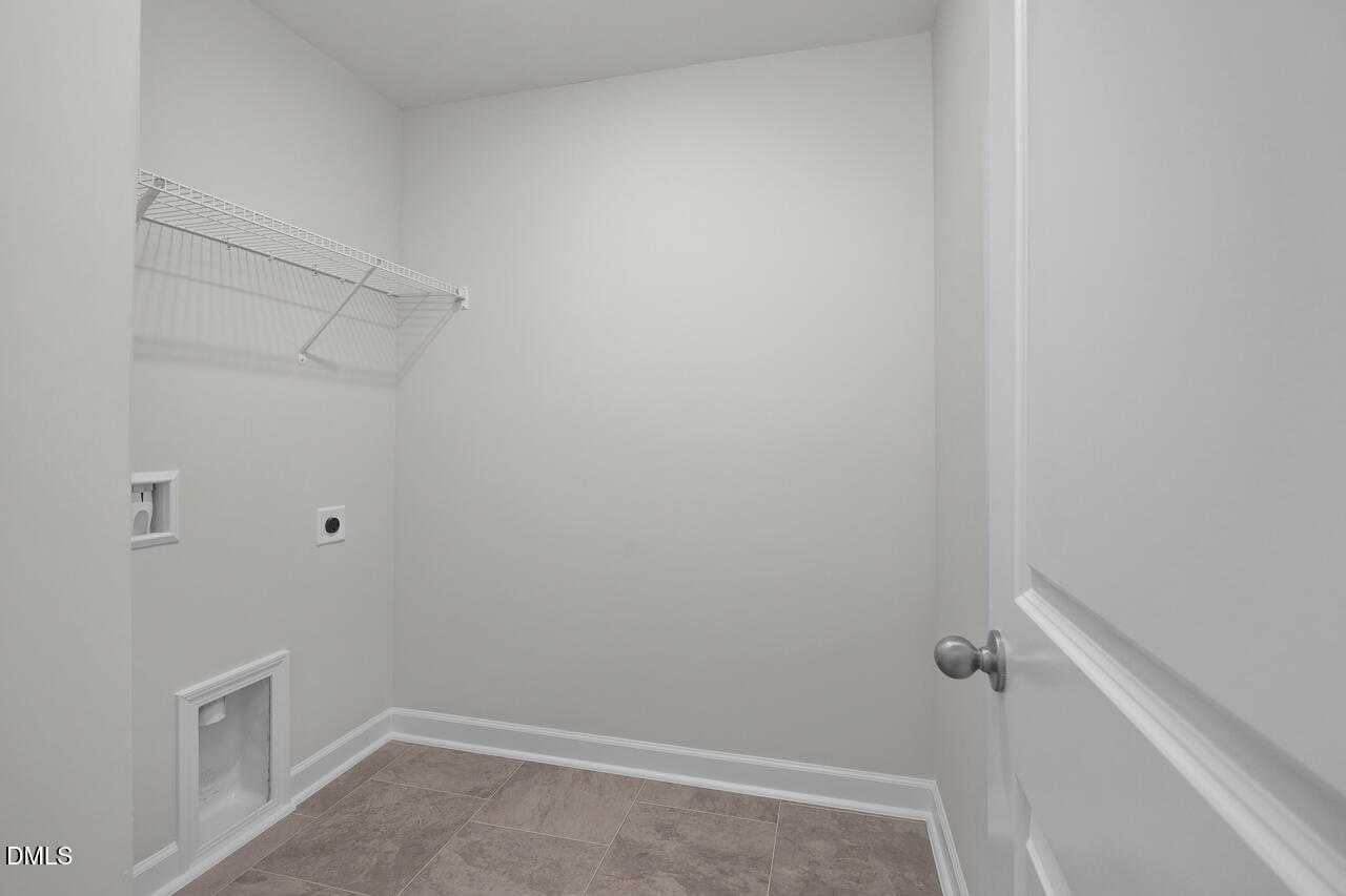 Spacious laundry room with wire shelving, washer-dryer hookups in Davidson Homes The Warren Interior, Fuquay-Varina, NC