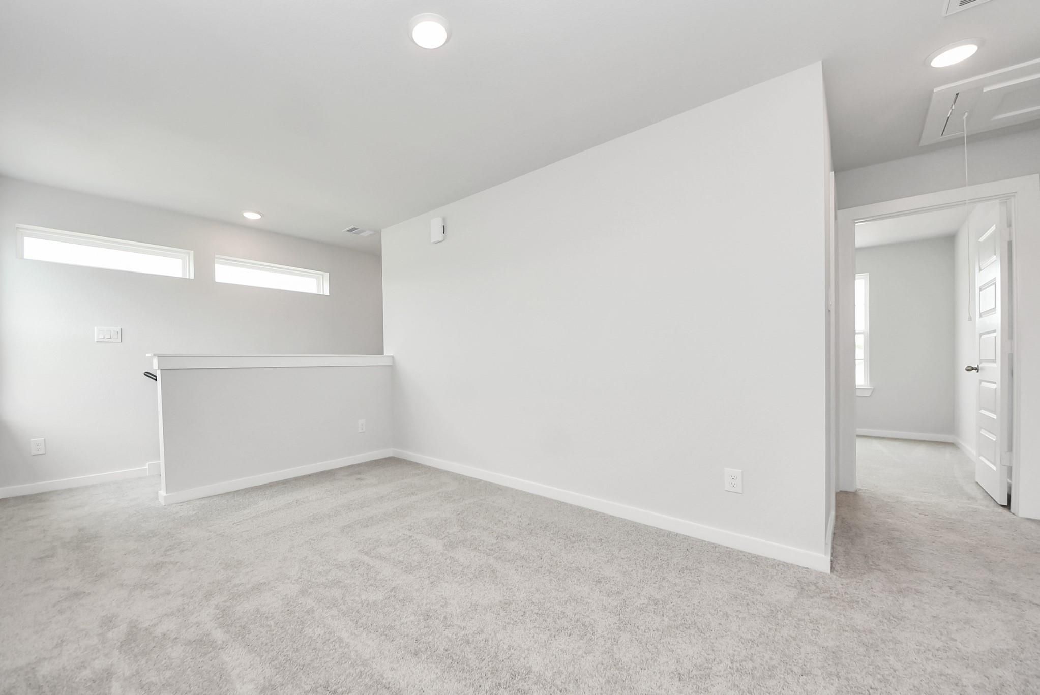 Bright, carpeted loft area in The Blanco E floor plan at The Villages at WestPointe in Dayton, Texas.