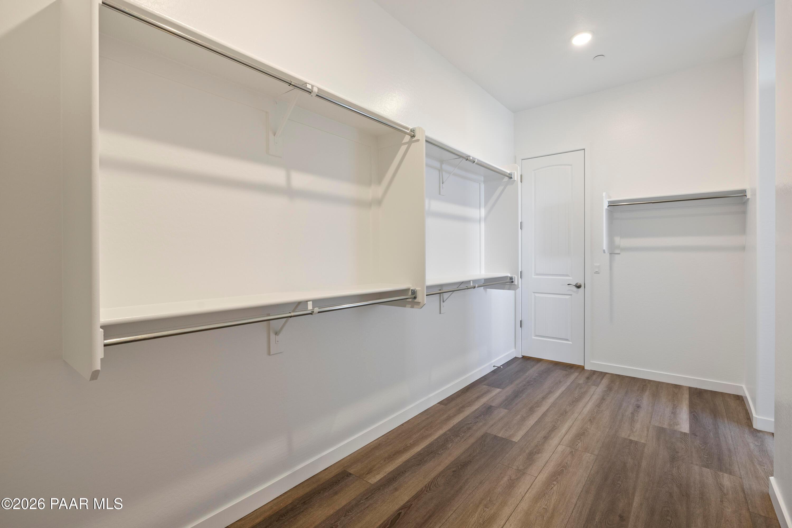 Spacious walk-in closet with white shelving, hanging rods and laminate flooring in Davidson Homes The Soleil E, Prescott, AZ