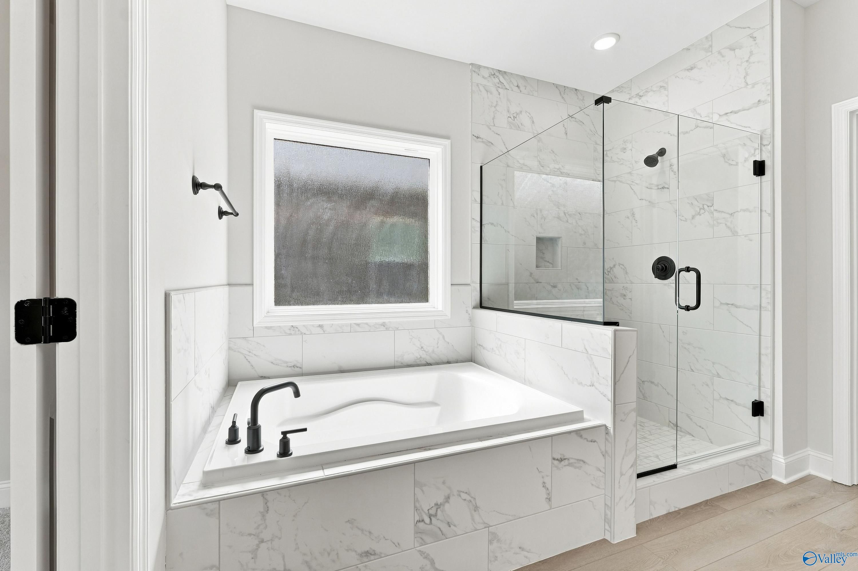 Modern master bathroom with marble tile, soaking tub, and glass shower in The Rockford B plan, Kendall Downs, Toney, AL.