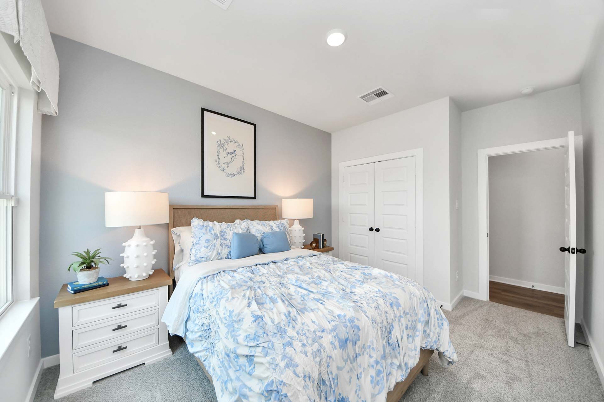 Cozy bedroom in The Enclave at Newport by Davidson Homes in Crosby, TX featuring blue floral bedding and modern decor.
