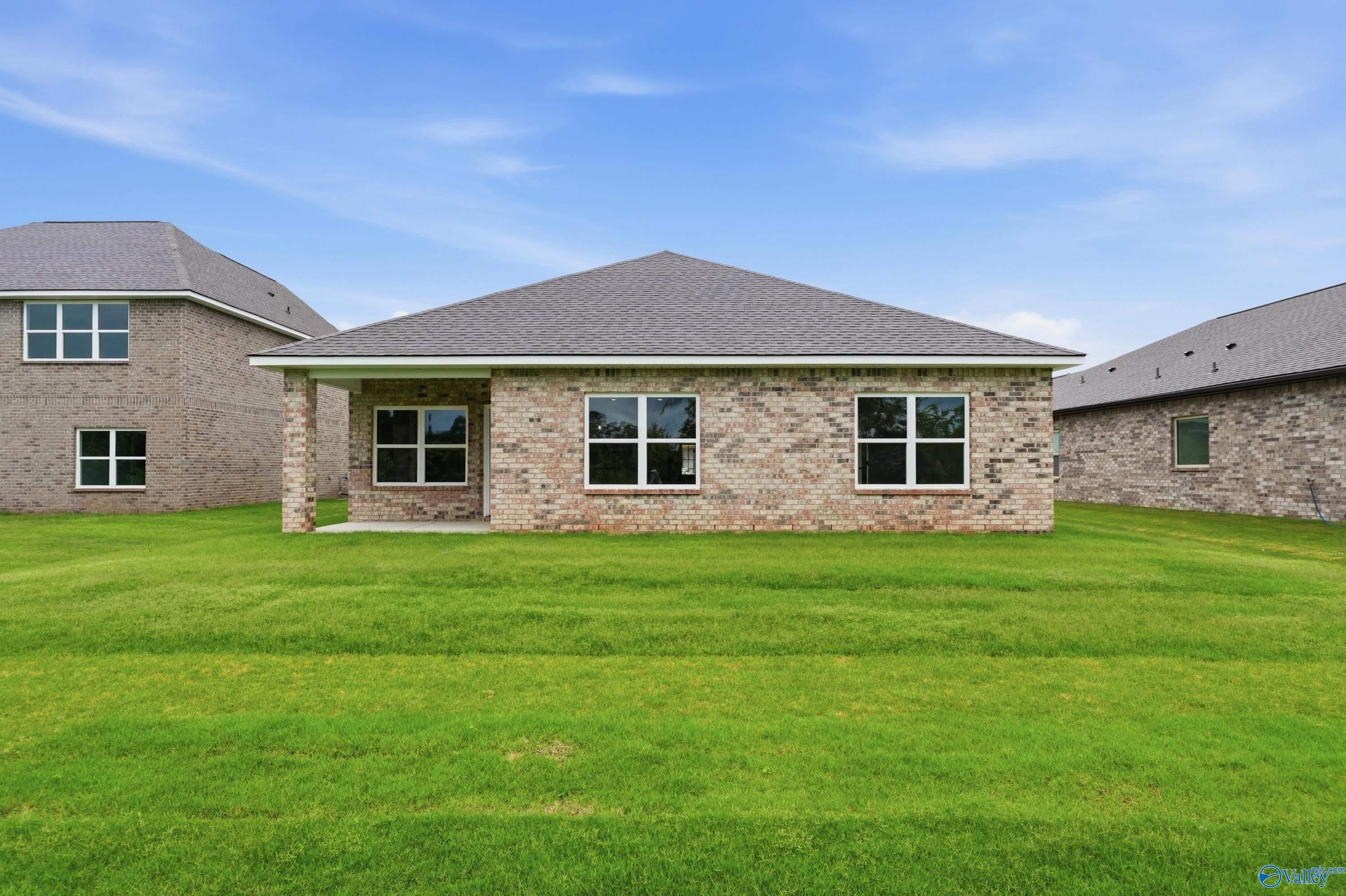 Rear exterior view of The Daphne C floor plan by Davidson Homes in Ivy Hills, Toney, Alabama with large grassy yard.
